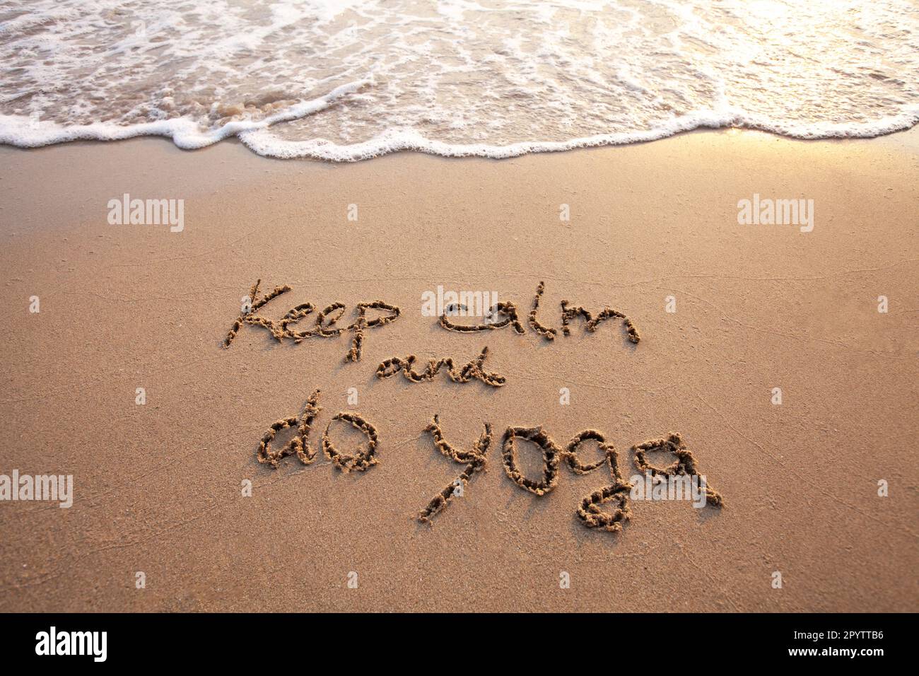 Bleib ruhig und mach Yoga, SMS auf Sand Stockfoto