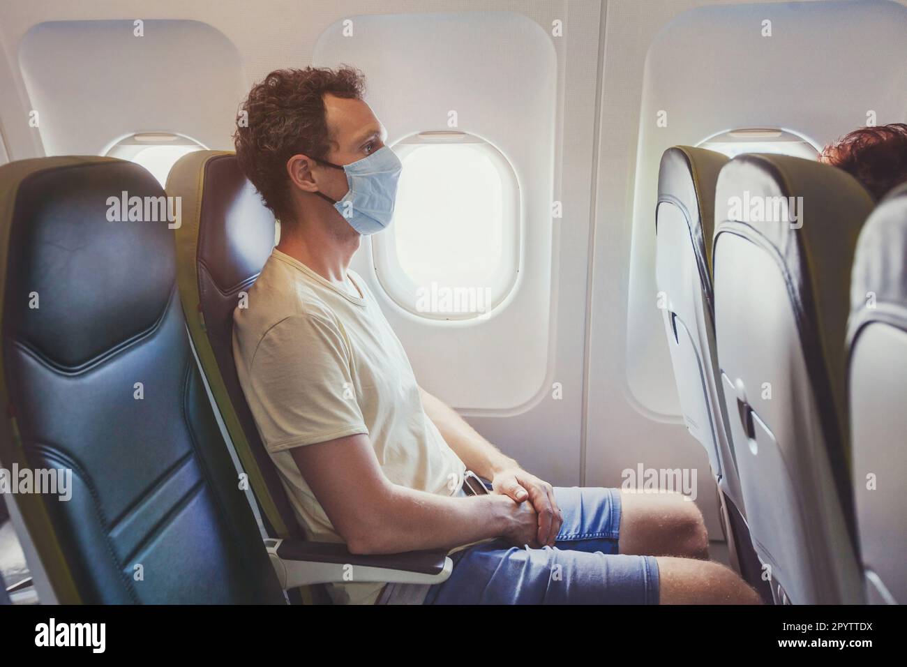Passagier trägt Gesichtsmaske im Flugzeug, Reisen während der Covid 19 Pandemie des Coronavirus Stockfoto Passagier trägt Gesichtsmaske im Flugzeug, Reisen während der Covid 19 Pandemie des Coronavirus Stockfoto