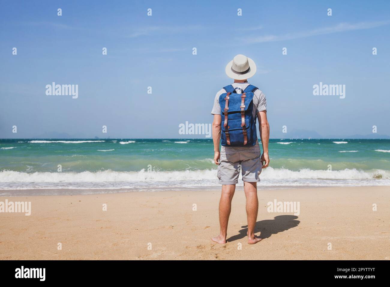 Touristenreisen am Strand, Tourismus auf dem Sommersee, Mann mit Rucksack steht barfuß auf dem Sand Stockfoto Touristenreisen am Strand, Tourismus auf dem Sommersee, Mann mit Rucksack steht barfuß auf dem Sand Stockfoto