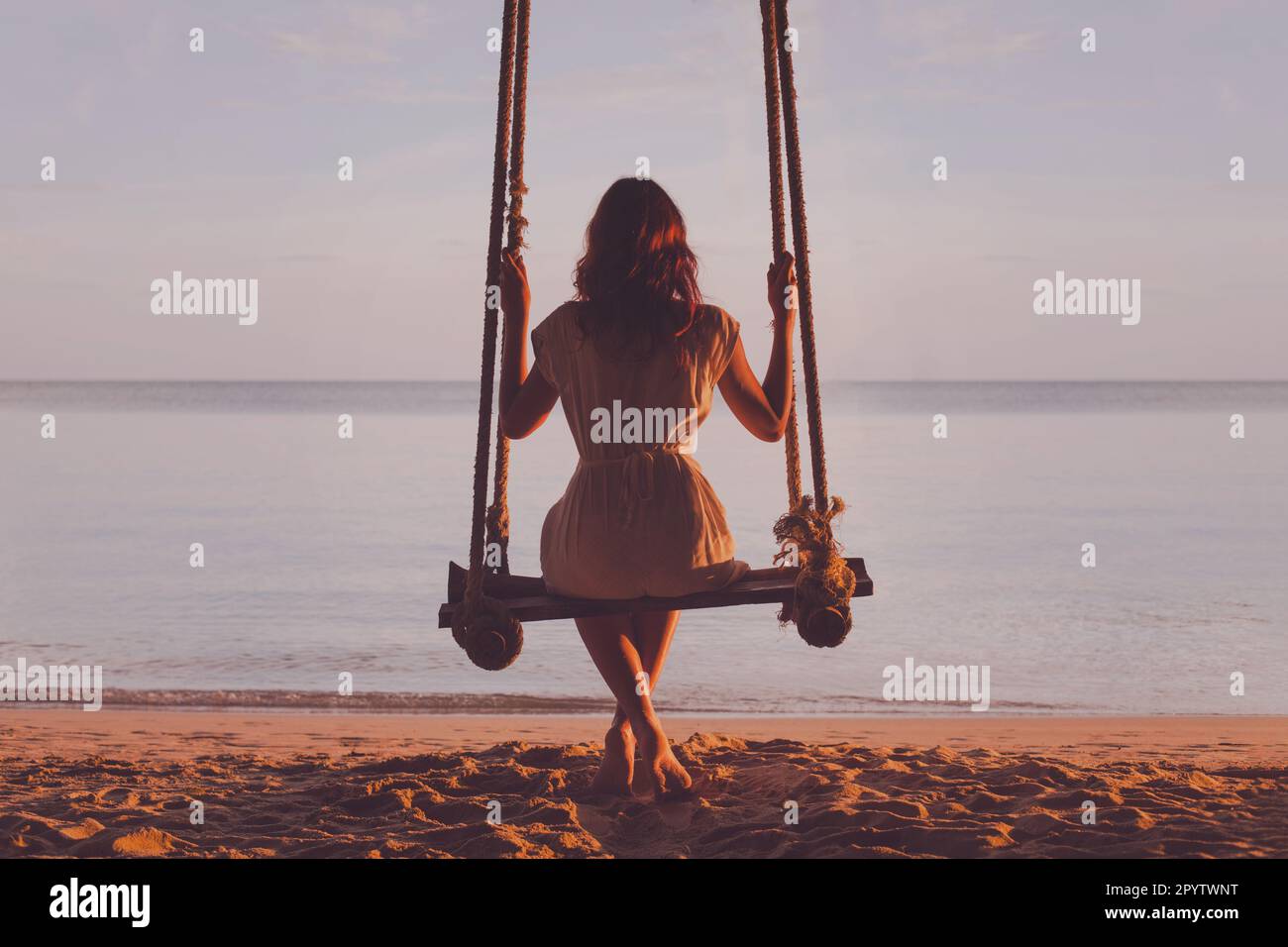 Reiseziel am Strand, Silhouette einer wunderschönen Frau, die auf einer Seilschaukel sitzt, Gelassenheit, Sommerurlaub Stockfoto Reiseziel am Strand, Silhouette einer wunderschönen Frau, die auf einer Seilschaukel sitzt, Gelassenheit, Sommerurlaub Stockfoto