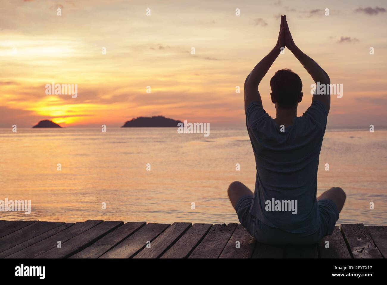 zen-Yoga und Meditation, Silhouette eines Mannes, der bei Sonnenuntergang am Pier sitzt, Achtsamkeit Stockfoto