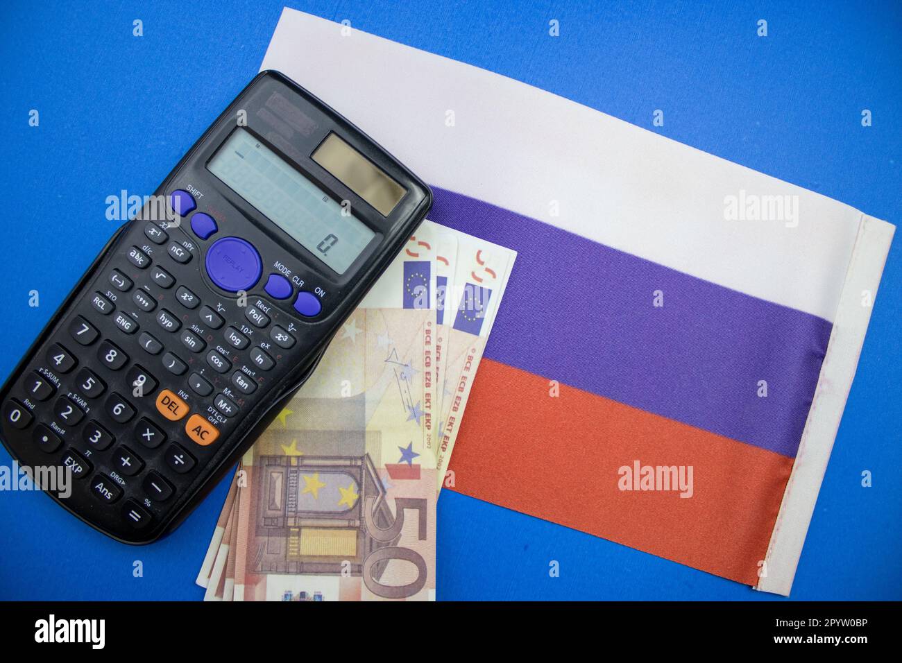 Die russische Flagge auf blauem Hintergrund, Euro und ein Taschenrechner darauf. Von oben fotografiert. Stockfoto