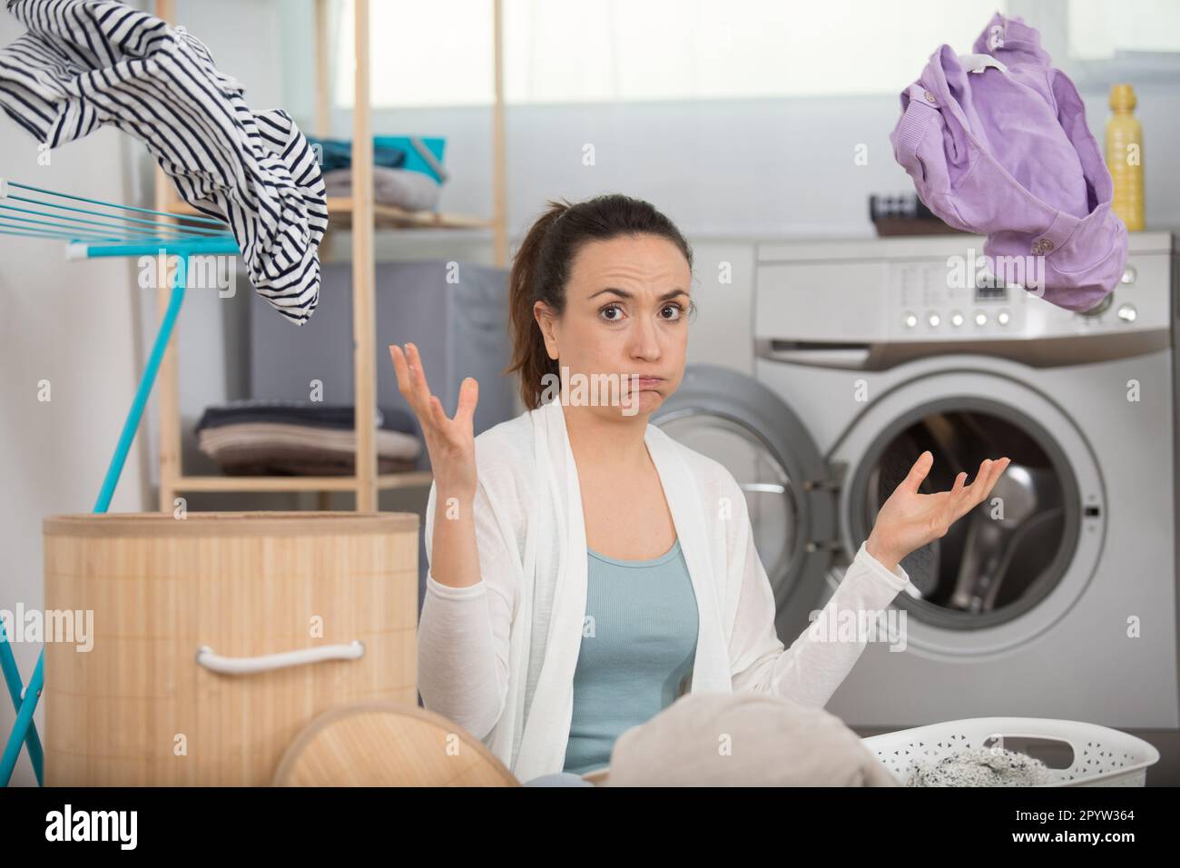 Frau überwältigt von Hausarbeit, Wäsche in die Luft zu werfen Stockfoto