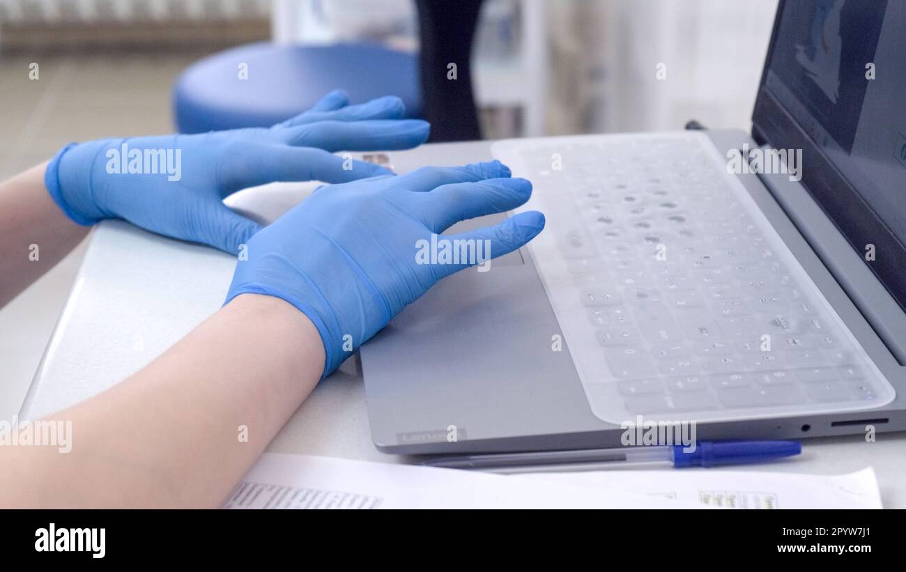 Arzt oder Krankenschwester Hände in blauen Nitril medizinischen Handschuhen Tippen auf Laptop Computer Tastatur im Krankenhaus Stockfoto