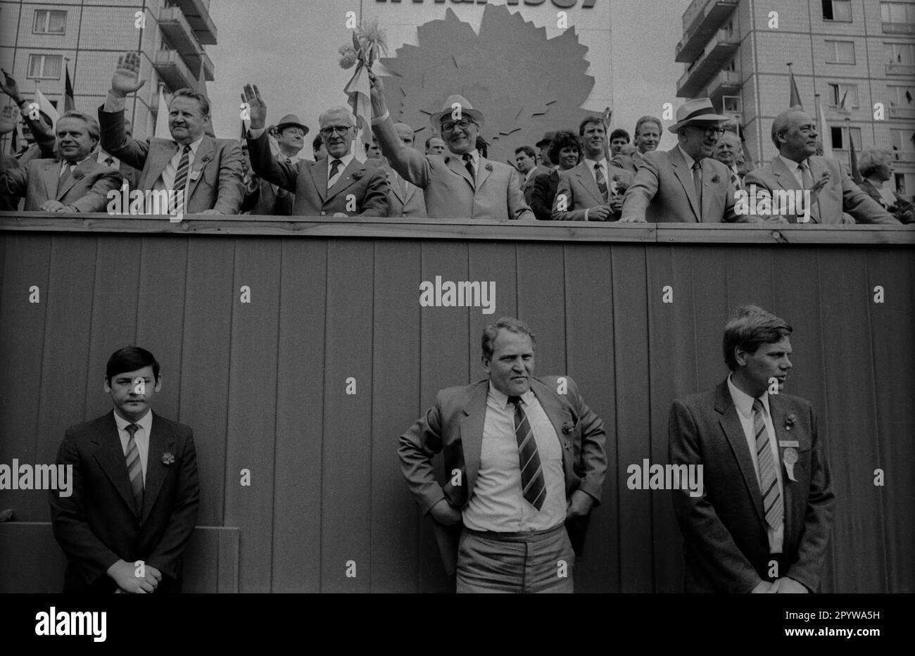DDR, Berlin, 01.05.1987, 1. Mai Rallye 1987 auf der Karl-Marx-Allee, Tribun, Erich Honecker is Hands Flowers, Left: Günter Schabowski, Willi Stoph (2. von links), Horst Sindermann (2. von rechts), Harry Tisch (1. von rechts), Wachen, Personal Security, [automatisierte Übersetzung] Stockfoto
