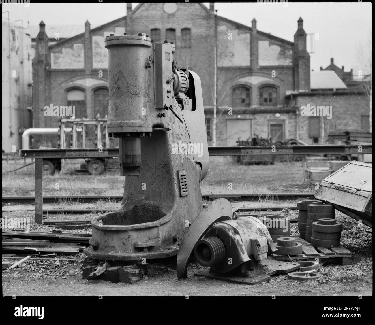 „Wildau (Bezirk Dahme-Spreewald, Brandenburg), Schwermaschinenbau AG Wildau, vormals Fabrik Ludwig Schwarzkopff, Berliner Maschinenbau AG, ab 1951 VEB Schwermaschinenbau ''Heinrich Rau'' (erbaut ab 1897). Ausrangierte Stanzmaschine vor der Schmiedehalle. Foto, Januar 1994." Stockfoto