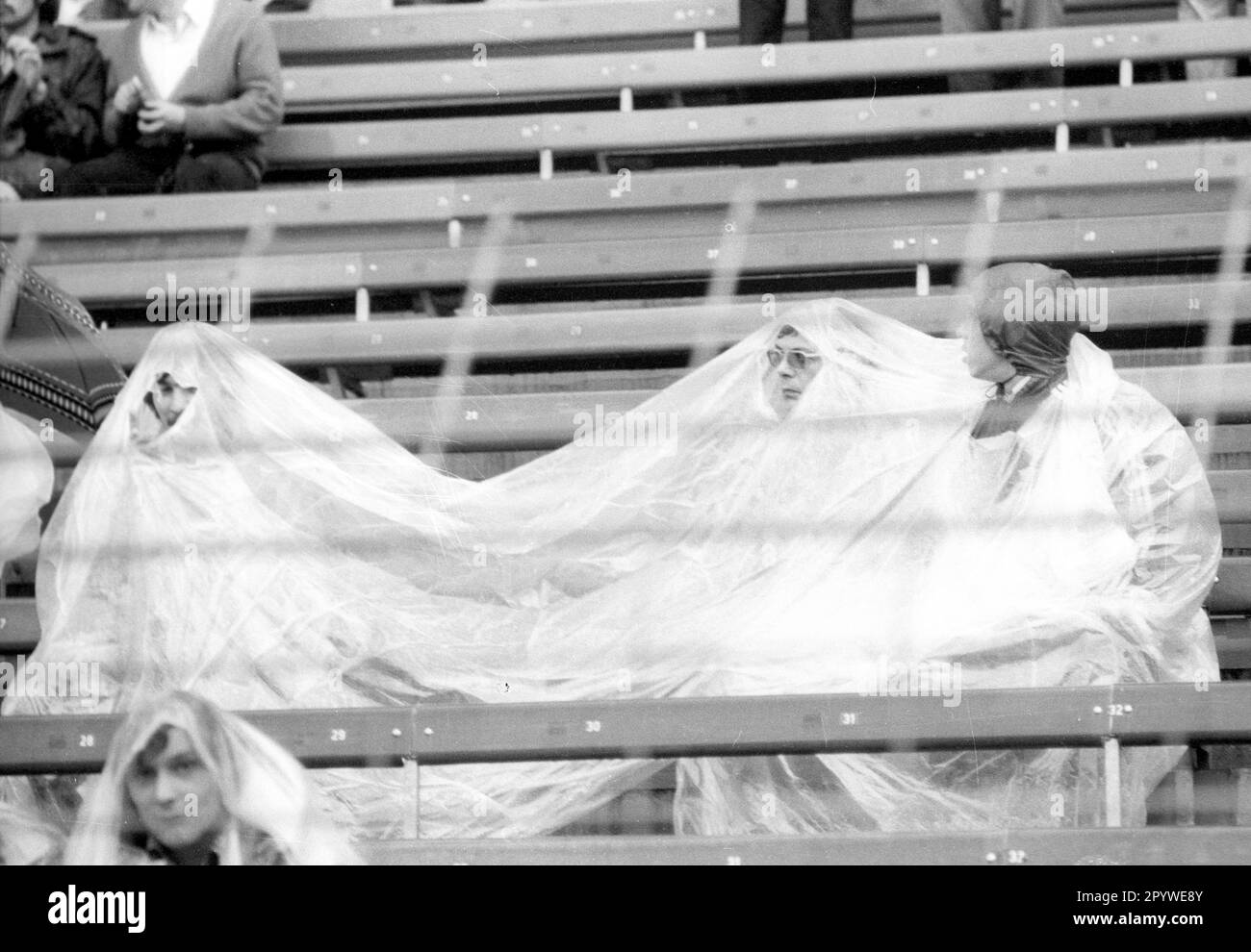 Fußballweltmeisterschaft 1974 2. Runde / BR Deutschland - Schweden 4:2 / 30.06.1974 in Düsseldorf / Zuschauer , Fans suchen Schutz vor dem Regen unter einer Plane oder einem Regenmantel. [Maschinelle Übersetzung] Stockfoto