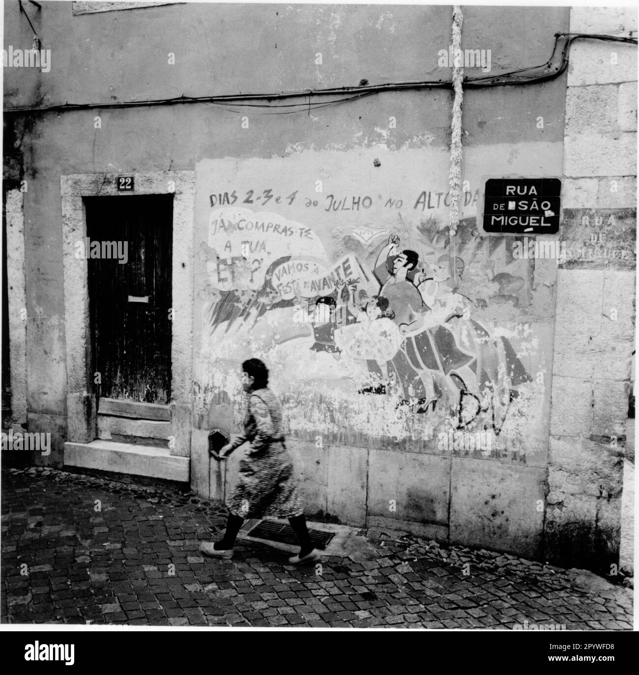 Lissabon - Lisboa (Portugal), Alfama, Rua de Sao Miguel. Straßenszene mit Blick auf Haus Nr. 22 mit politischem Wandgemälde. Eine Frau läuft die Straße entlang. Schwarz-Weiß, 6 x 6 cm Negativ. Foto, 1992. Stockfoto