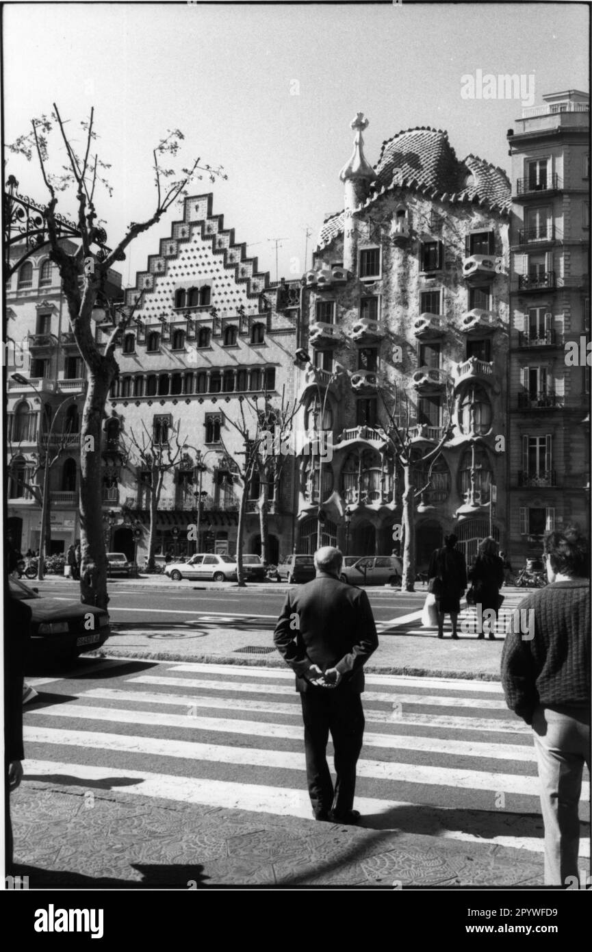 Barcelona (Spanien). Casa Batllo (1877 erbauter Apartmentblock, von Antoni Gaudi in den Jahren 1905-07 umgestaltet). Casa Batllo (rechts), daneben Casa Amatller (1898 erbaut, neue Fassade von Puig i Cadafalch). Davor warten Leute am Zebraübergang. Straßenszene, schwarz-weiß. Foto, 1993. Stockfoto