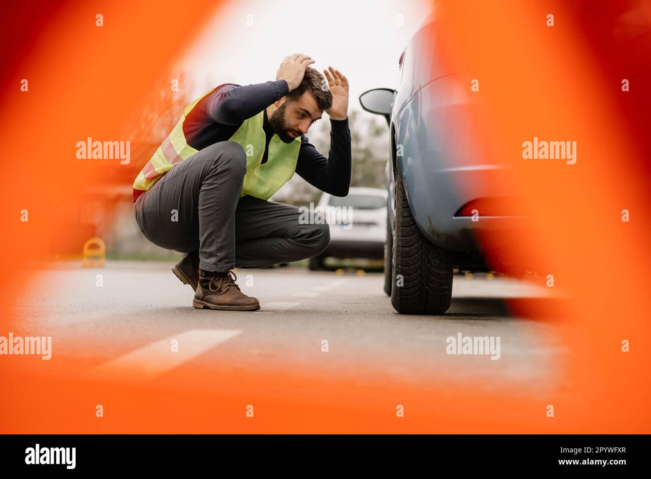 Ein Mann steht neben seinem formell gekleideten Auto und sieht besorgt aus wegen des Motorproblems. Stockfoto