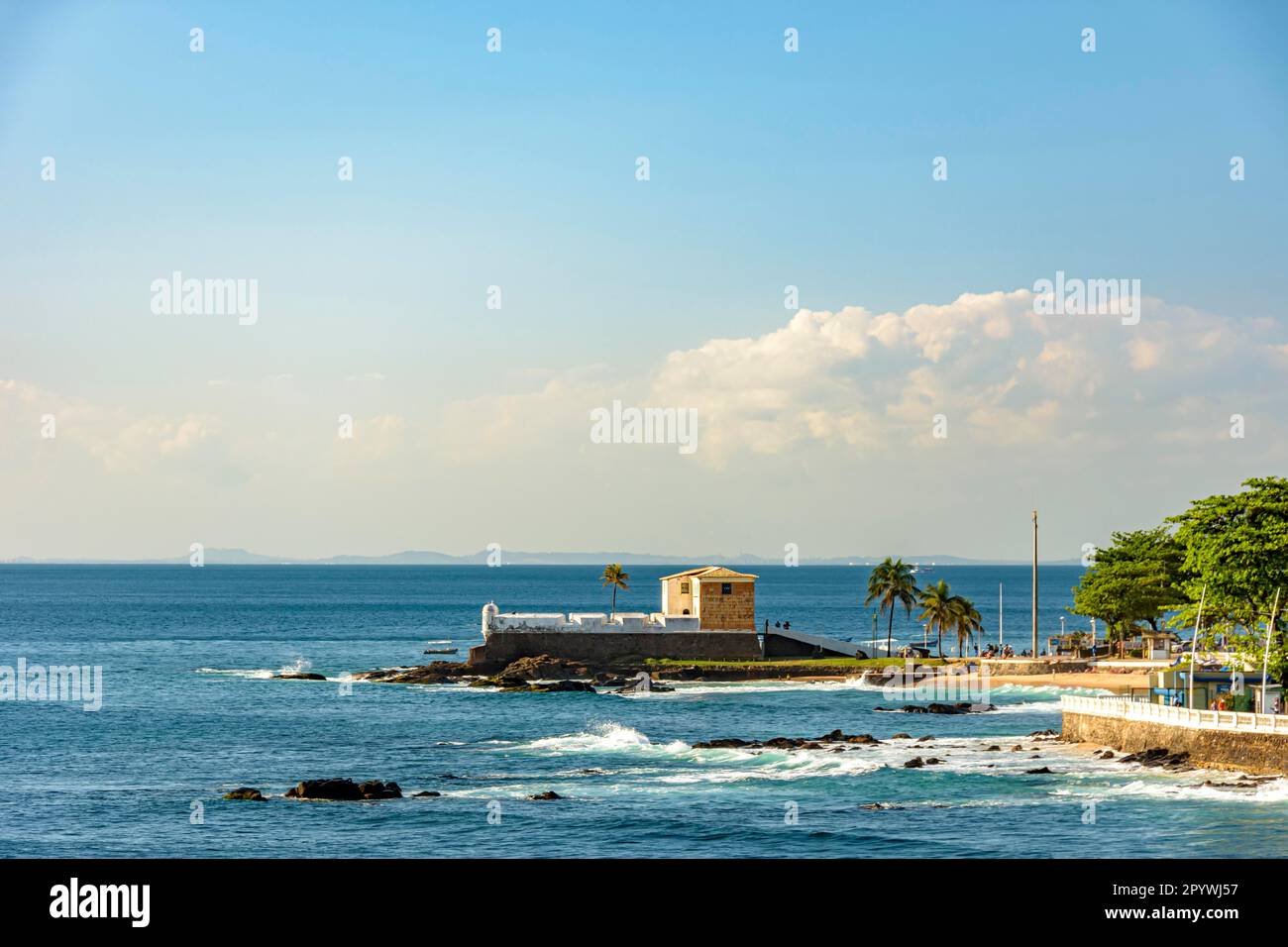 Malerischer Blick auf das alte portugiesische Fort Santa Maria im Kolonialstil in Barra Beach, Salvador, Brasilien mit Palmen, die über der zerklüfteten Küste stehen Stockfoto