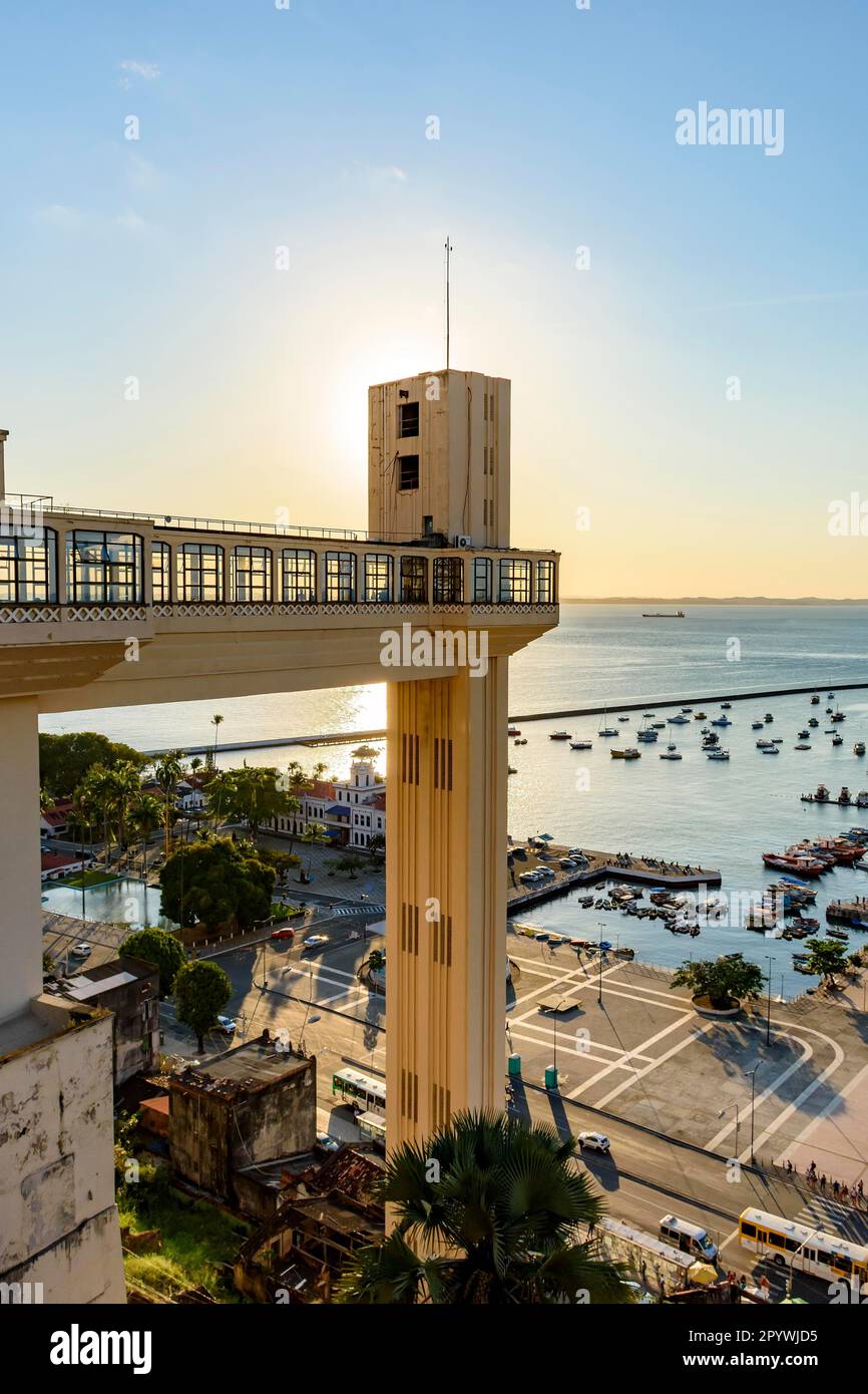 Blick von oben auf die Bucht von All Saints, den Aufzug Lacerda und den Hafenpier mit seinen Booten während des Sonnenuntergangs in der Stadt Salvador, Bahia, Brasilien Stockfoto