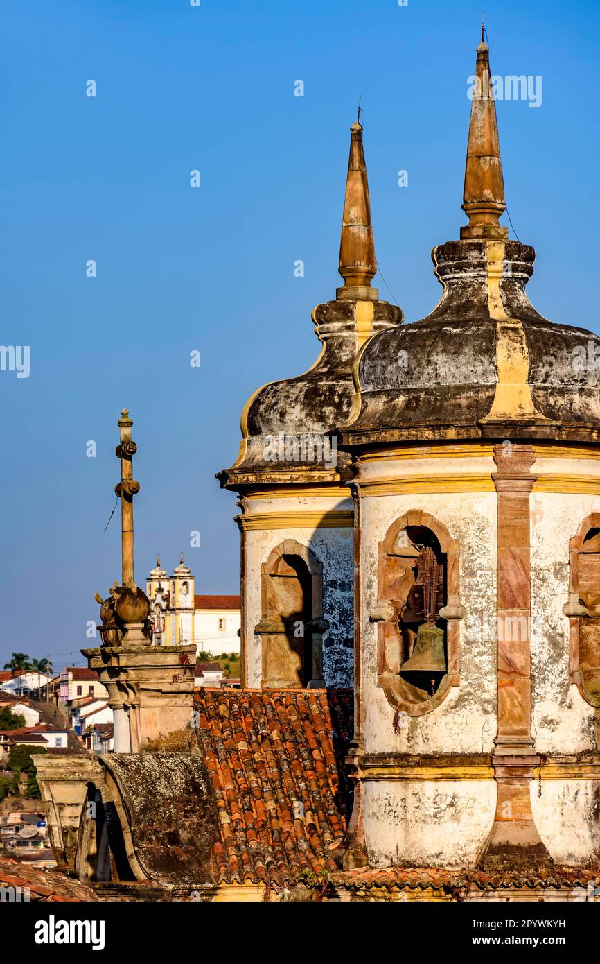 Glockenturm mit barocken Kirchen in der Dämmerung mit der berühmten historischen Stadt Ouro Preto im Hintergrund, Brasil Stockfoto