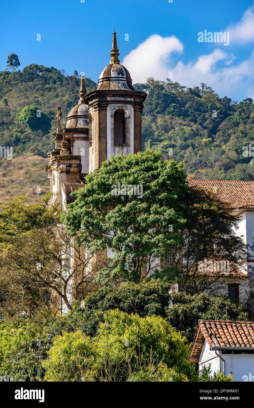 Turm einer alten barocken Kirche inmitten der Vegetation der historischen Stadt Ouro Preto in Minas Gerais, Brasilien Stockfoto