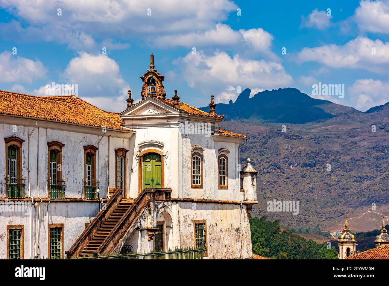 Antike barocke Kirche in der Stadt Ouro Preto mit den Hügeln und dem Gipfel von Itacolomi im Hintergrund an einem sonnigen Nachmittag, Brasilien Stockfoto