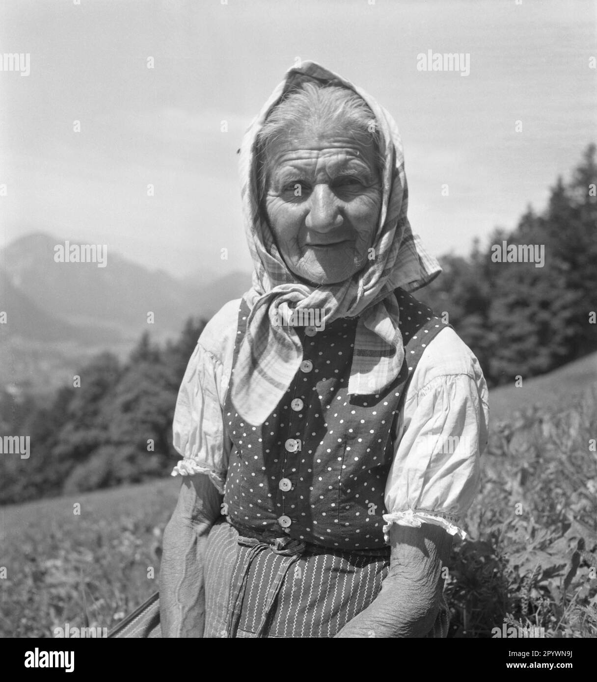Eine alte Bauernfrau in traditioneller Kleidung auf einem Feld. Stockfoto