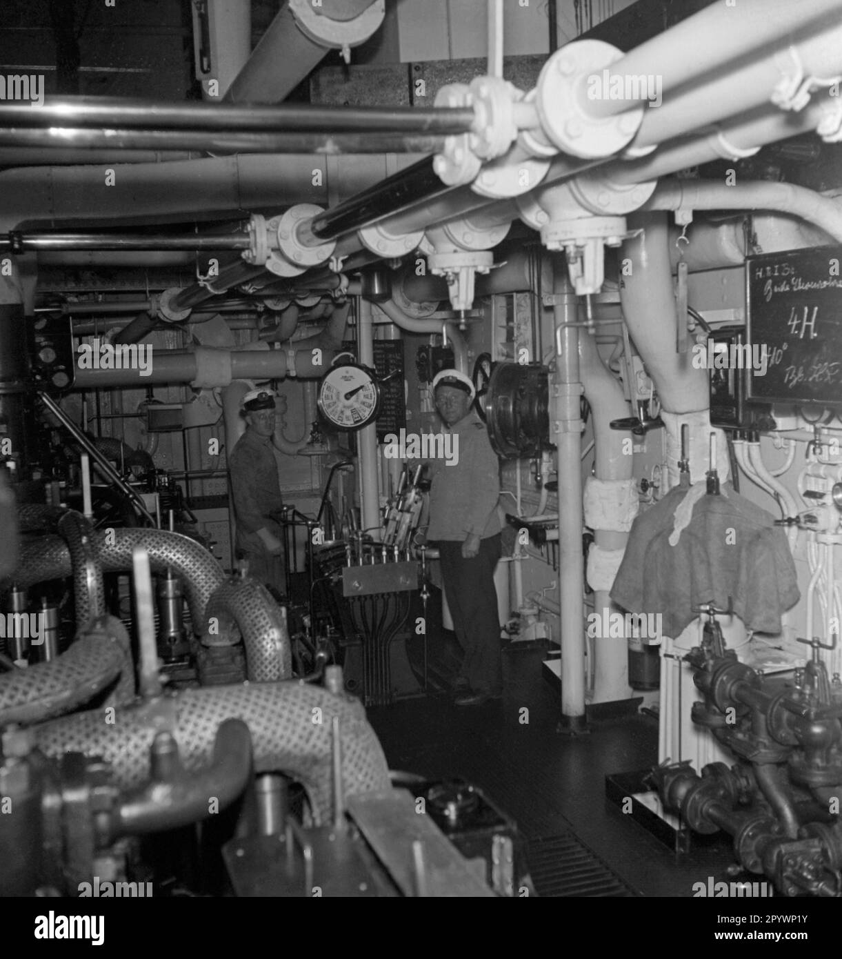 Zwei Mechaniker im Maschinenraum des Passagierschiffs 'Monte Rosa' in den 1930er. Hier ist der Maschinenraum-Telegraf, mit dem Richtung und Geschwindigkeit der Reise von der Brücke aus bestimmt werden konnten. Stockfoto