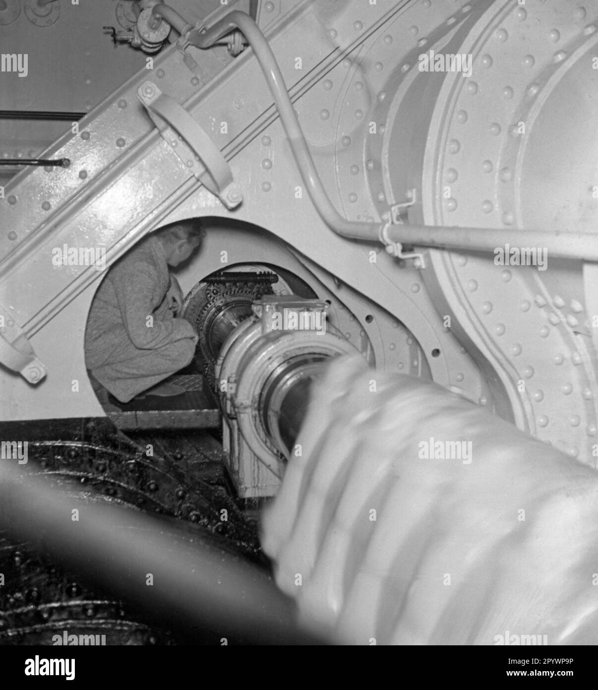 'Ein Mechaniker auf einer Antriebswelle im Maschinenraum des 'Monte Rosa' der Reederei Hamburg Süd in den 1930er Jahren.' Stockfoto