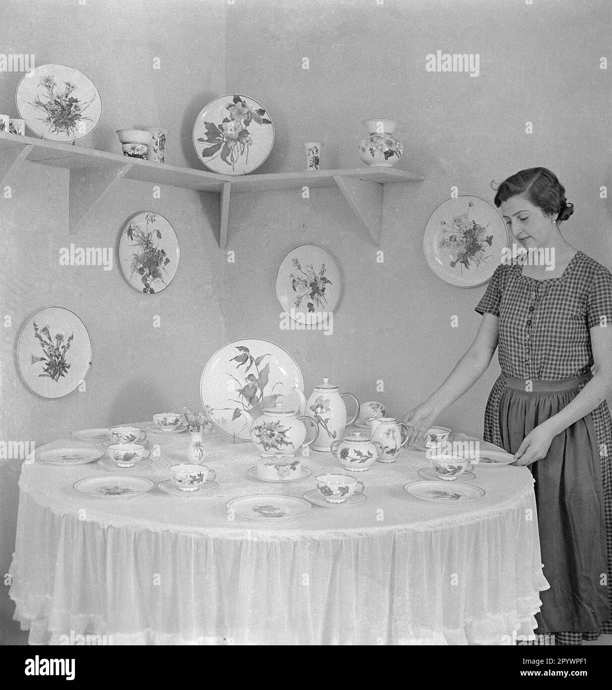 Eine Frau im Haus Immergruen präsentiert Gerichte mit bemalten Wildblumen. Unbezahltes Foto von etwa 1935. Stockfoto