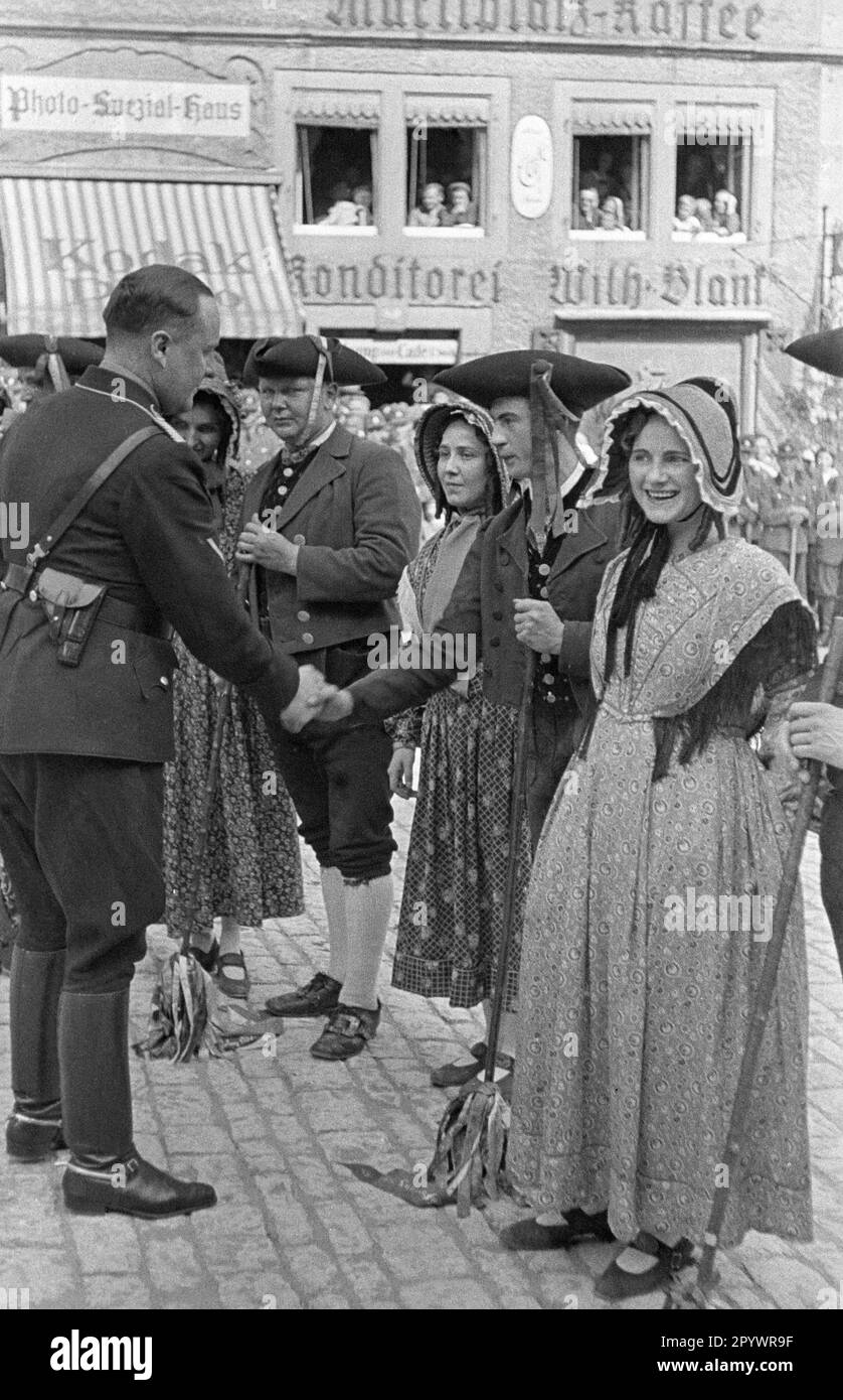 Ein Mann in SS-Uniform schüttelt sich mit einer Schauspielerin in historischem Kostüm die Hand. Stockfoto