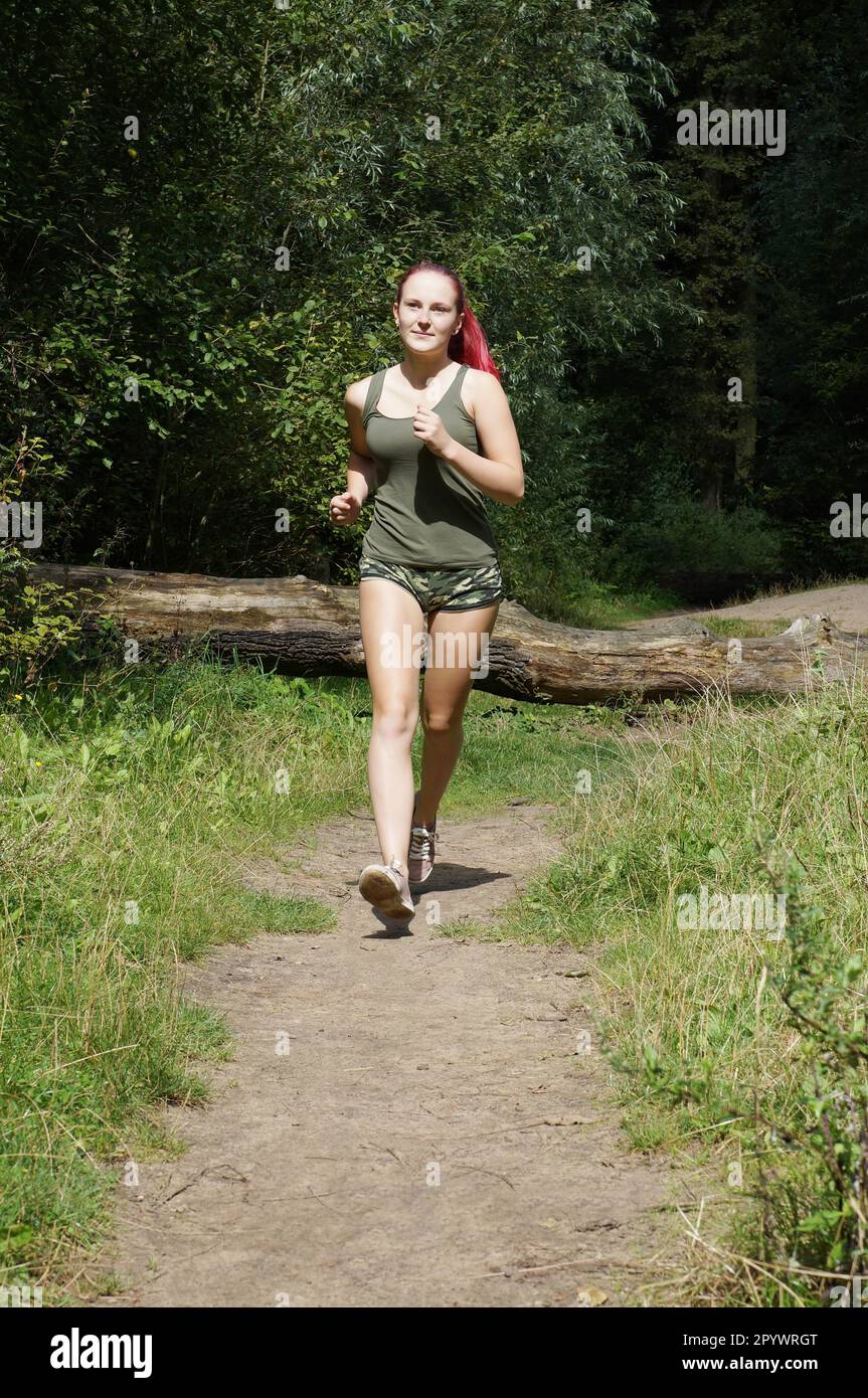 weibliche Jogger läuft auf einem Waldweg Stockfoto