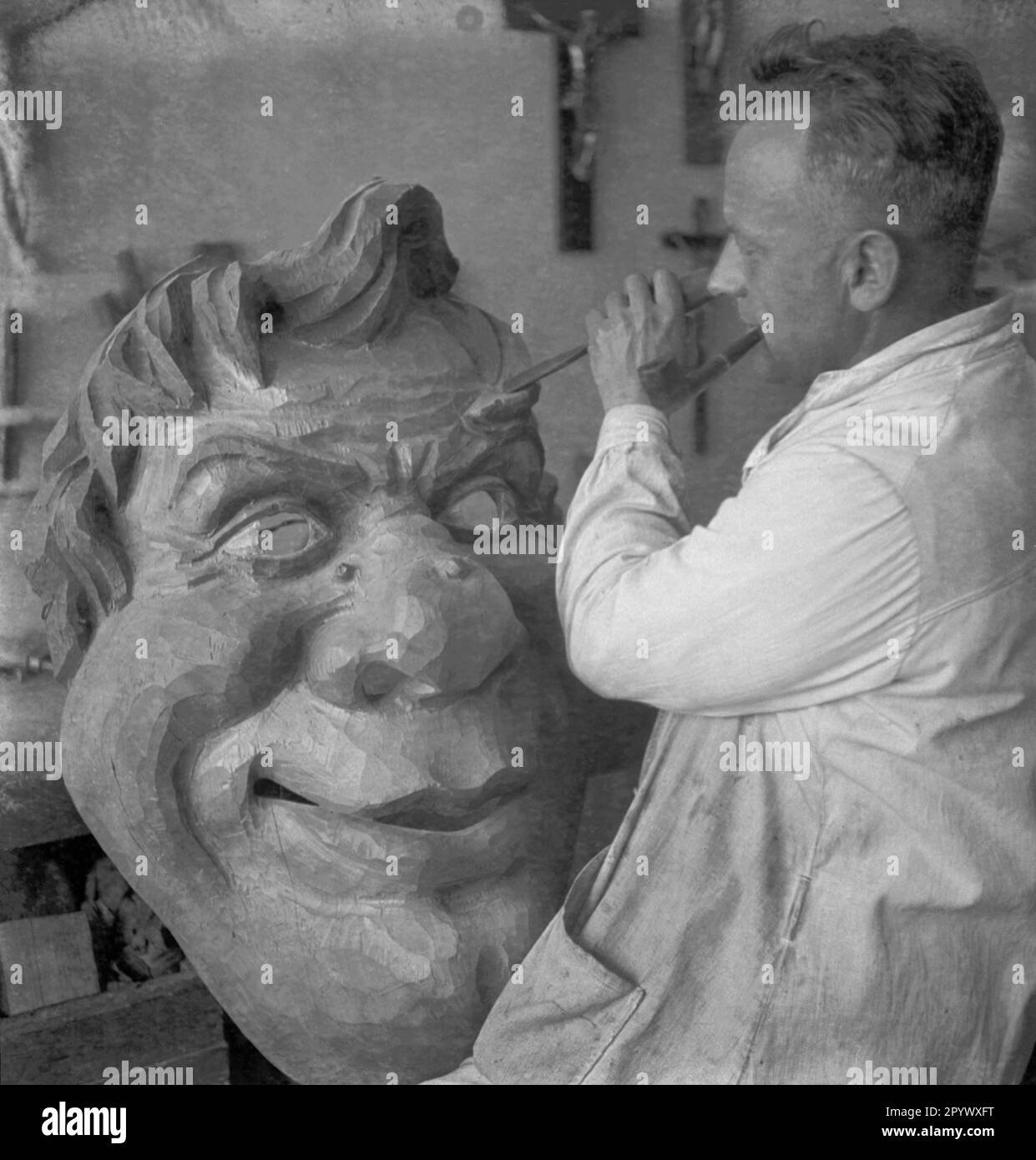 Ein Künstler schnitzt eine übergroße Holzmaske in einer Werkstatt in Oberbayern (unbedecktes Bild). Stockfoto