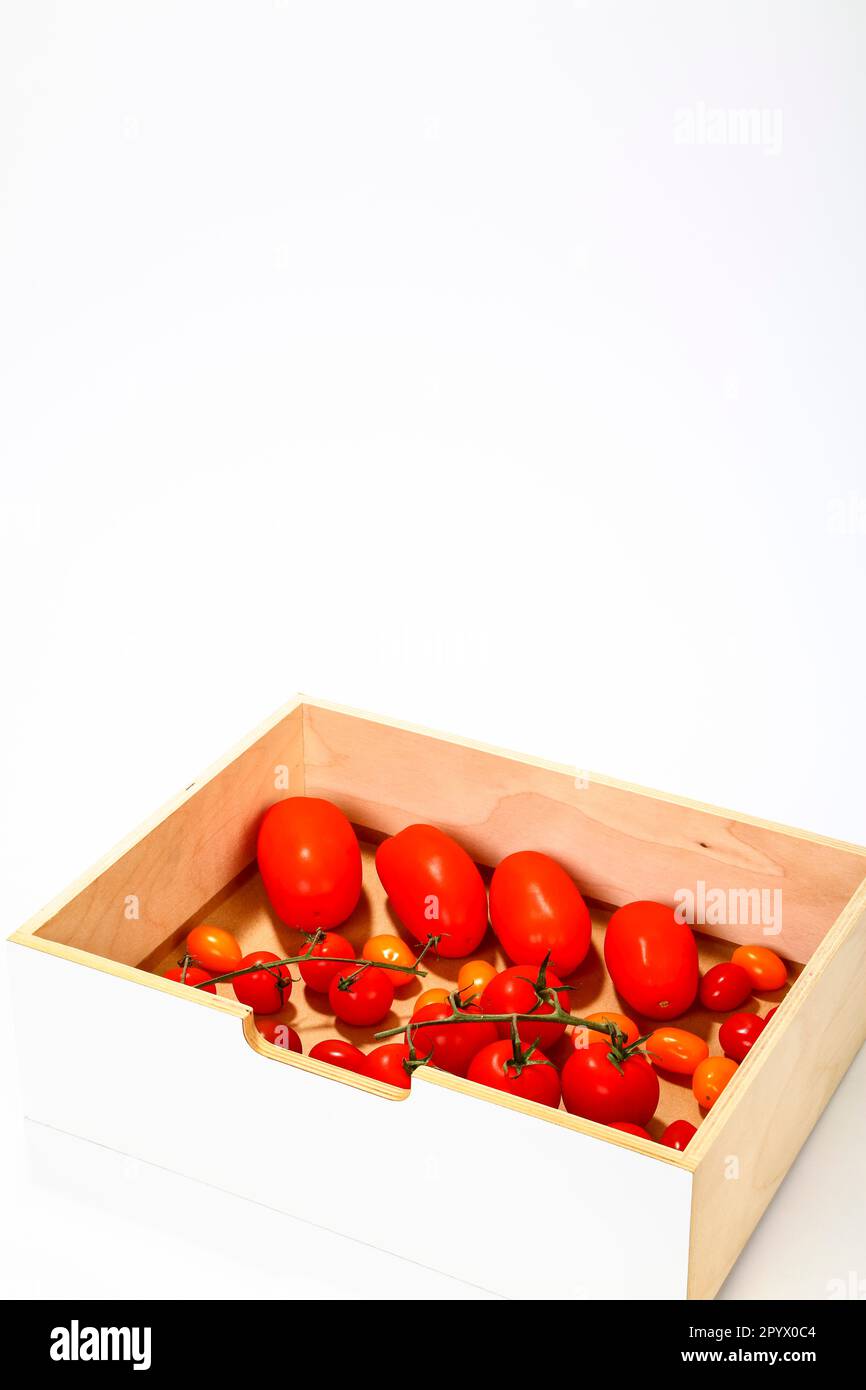 Pflaumenrebe und Kirschtomaten in einem Holzkasten isoliert auf weißem Hintergrund Stockfoto