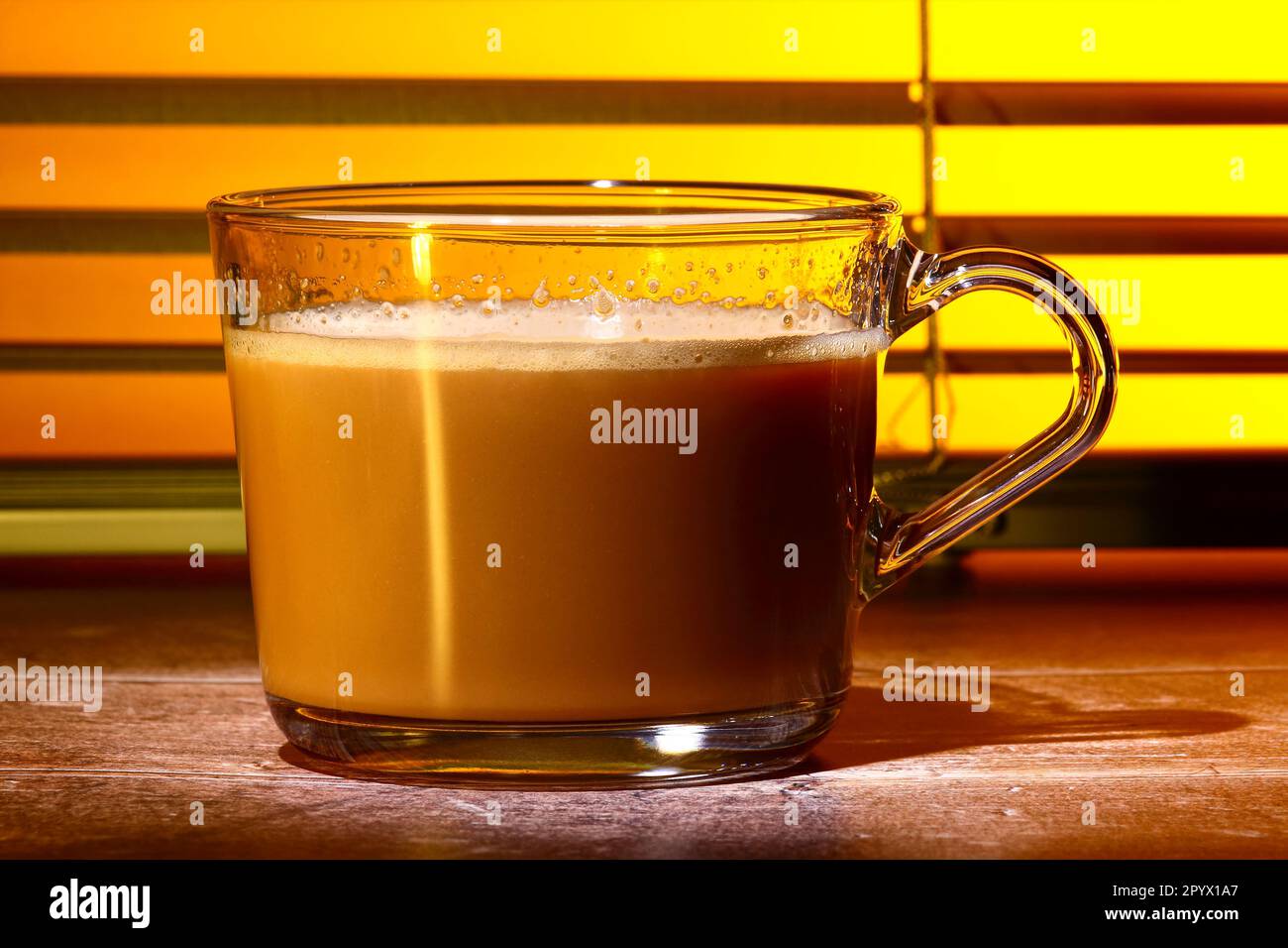 Glas-Kaffeetasse gefüllt mit Kaffee Set vor einem Küchenfenster-Jalousien Stockfoto