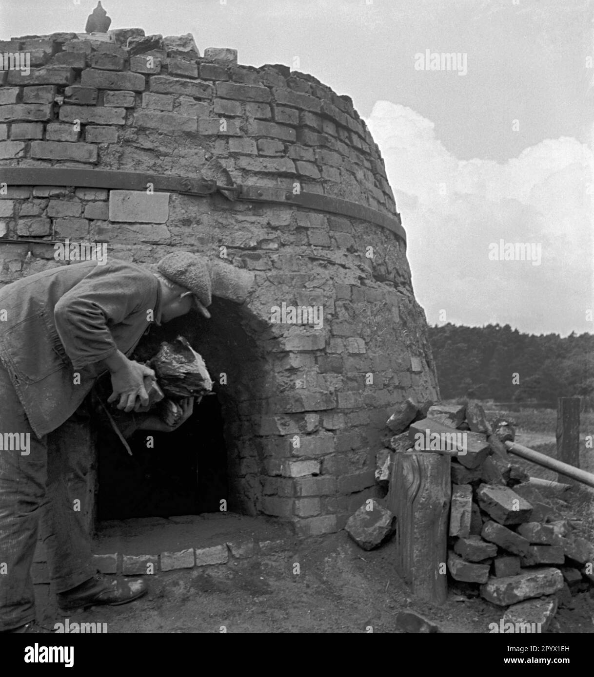 Der Mensch verbrennt Stämme, um Teer zu gewinnen, indem er Holz durch den Prozess der pyrolytischen Zersetzung verkohlt. Stockfoto