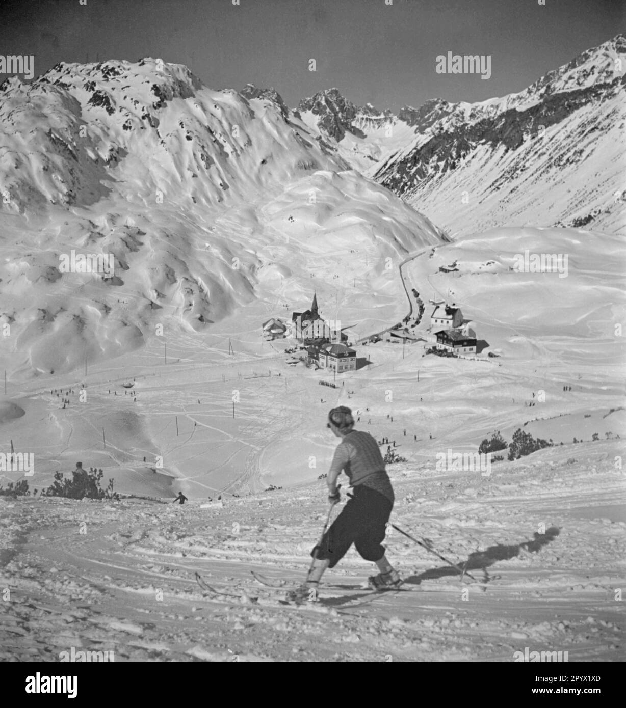 Ein Skifahrer fährt die Piste hinunter in das Tal. Unbezahltes Foto, wahrscheinlich im Winter 1933/1934. Stockfoto