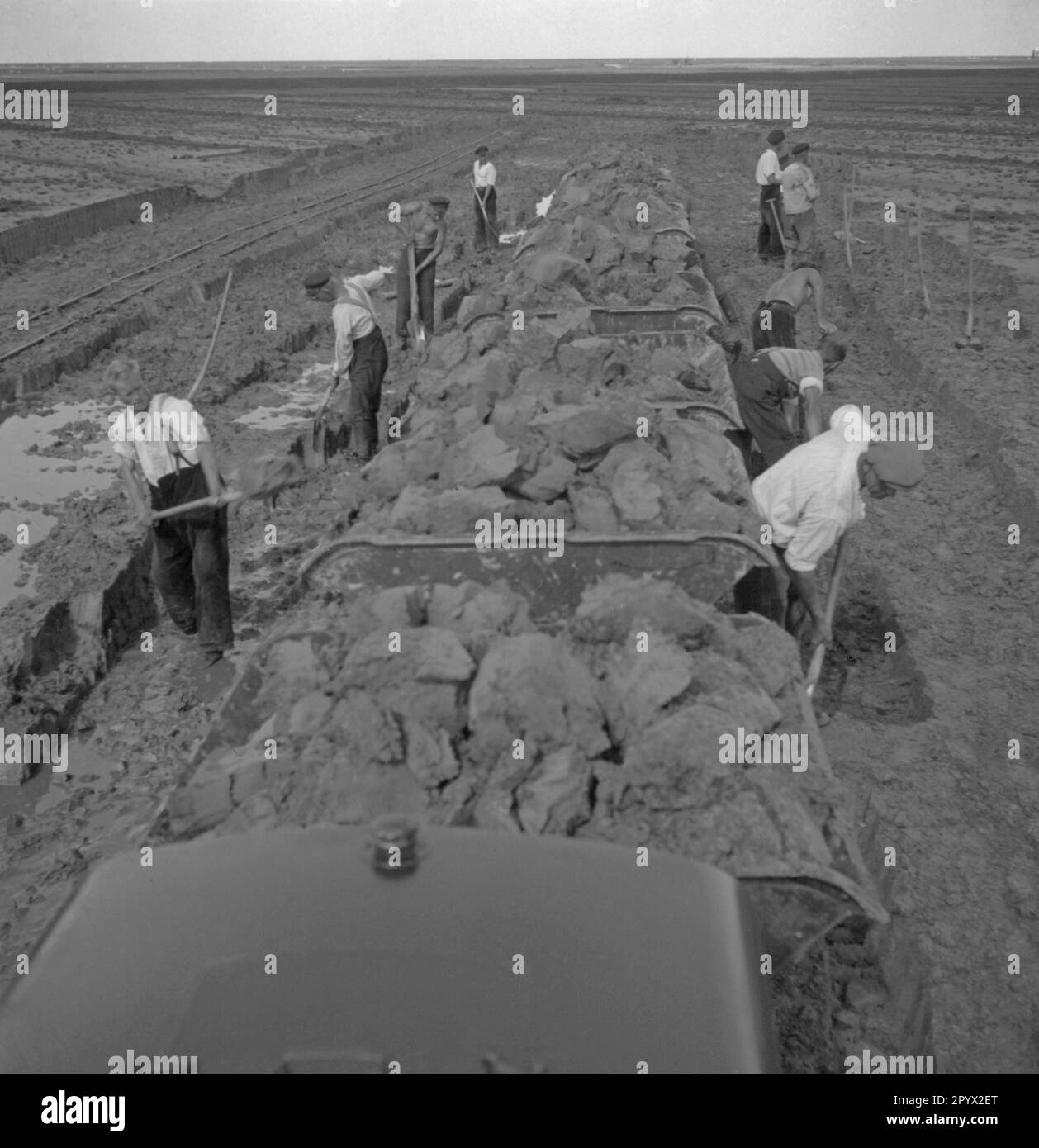 Arbeiter, die Schlamm auf einen Güterwagen schaufeln. Unbezahltes Foto, wahrscheinlich 1934 aufgenommen. [Maschinelle Übersetzung] Stockfoto