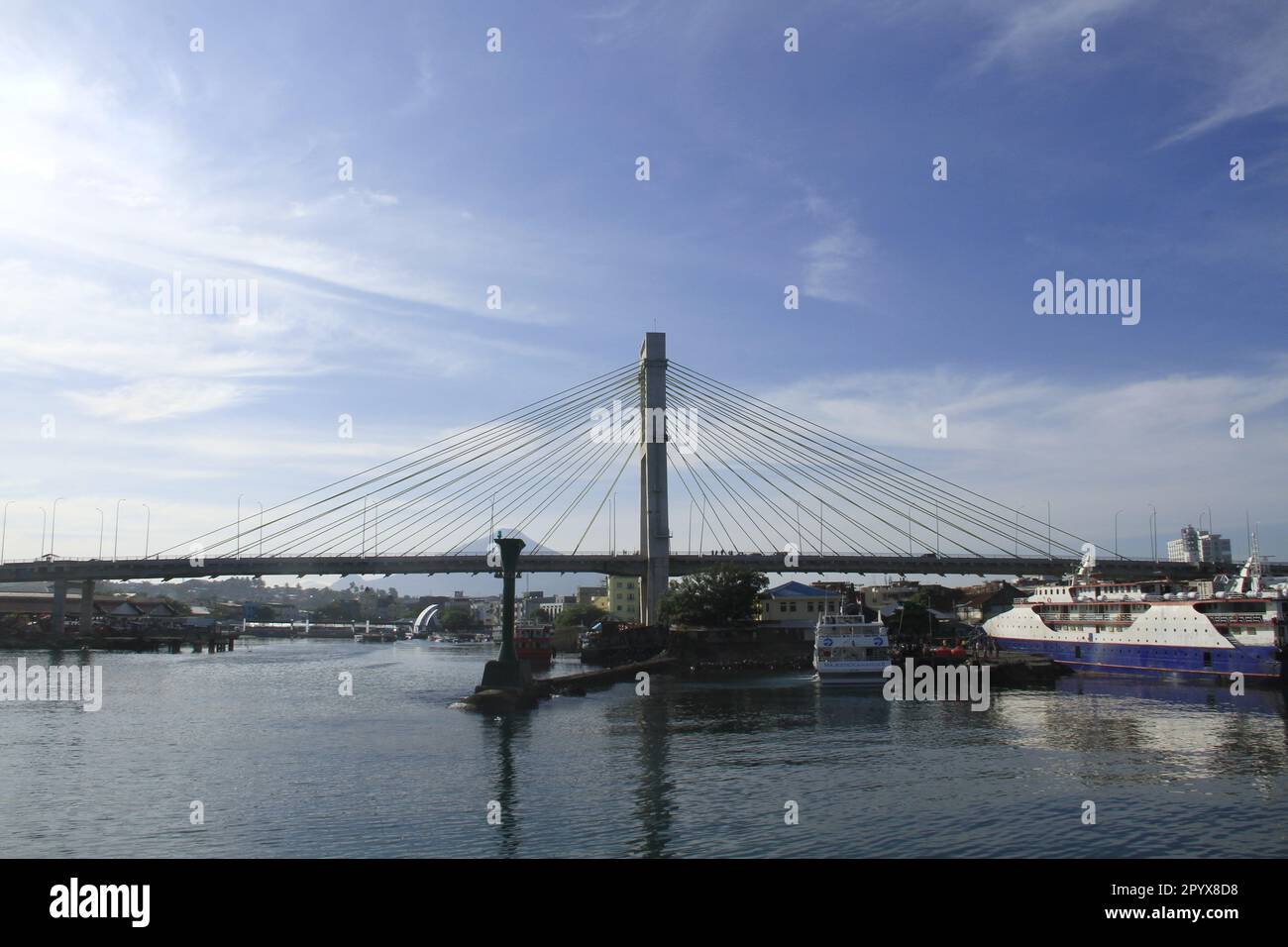 Blick auf die Stadt Manado in Indonesien vom Meer aus. Sie können die majestätische Brücke, Schiffe und Berge im Hintergrund sehen. Stockfoto