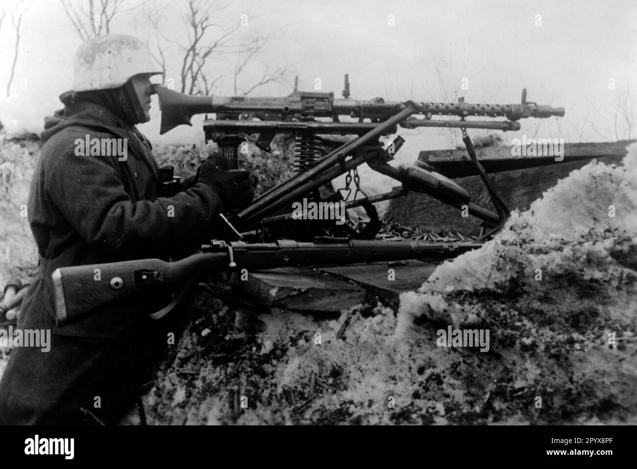 Deutscher Soldat an der Ostfront bei Kaganovicha. In der Grabenwand befindet sich ein MG 34 in einem Wagen, daneben befindet sich ein Karabiner 98k. Foto: Knödler [maschinelle Übersetzung] Stockfoto