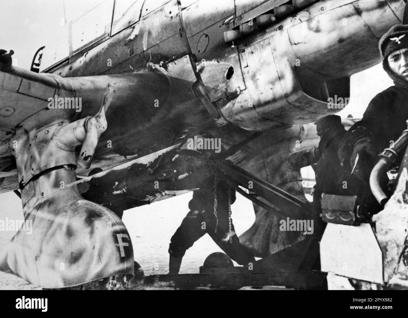 Bodenbesatzung, die eine schwere Bombe unter dem Rumpf eines Junkers Ju 87 anzündet. Das Bild zeigt die Propeller der sogenannten Jericho-Trompete, die das heulende Geräusch erzeugte, als das Flugzeug fiel. Foto: Roesch. [Maschinelle Übersetzung] Stockfoto