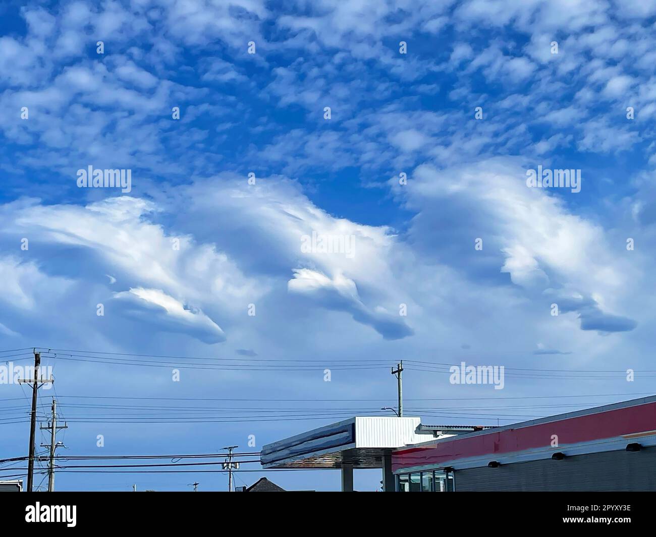 Eine ungewöhnliche Wolkenformation am blauen Himmel, über einer Straße. Stockfoto