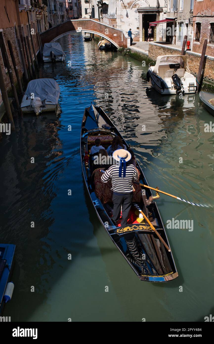 Blick auf einen Gondoliere von der Rückseite einer Gondel in einem engen Kanal in Venedig Stockfoto