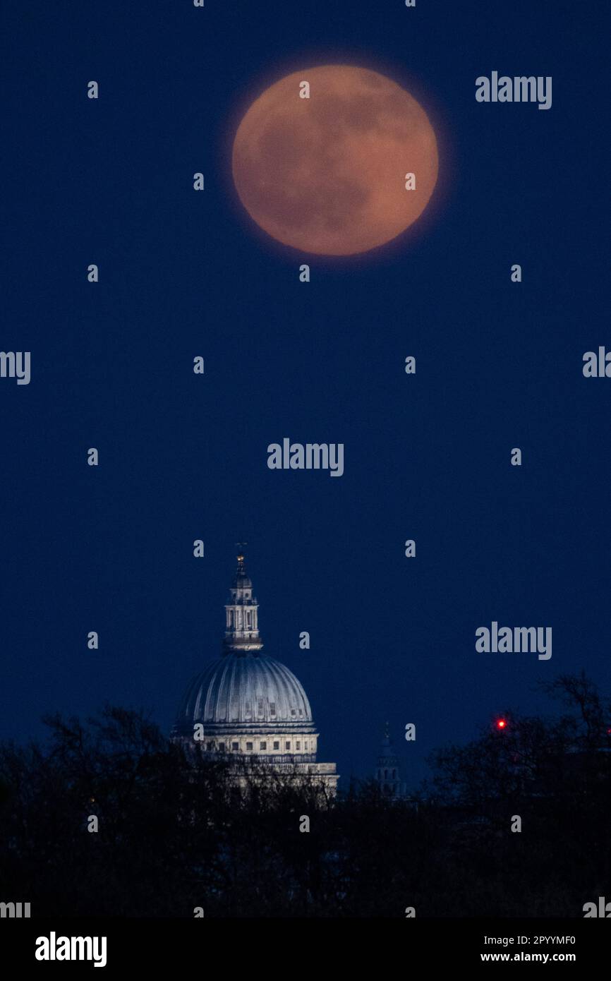 London, Großbritannien. 5. Mai 2023 UK Weather – der Blumenmond erhebt sich hinter der St Paul's Cathedral, vom Primrose Hill aus gesehen. Der Vollmond dieses Monats ist nach dem Almanach des Alten Bauern für die üppigen Blumen benannt, die diesen Monat entstehen. Der Vollmond erhebt sich in der Nacht vor der Krönung von König Karl III., der für seine Liebe zu Pflanzen und Blumen bekannt ist. Kredit: Stephen Chung / Alamy Live News Stockfoto