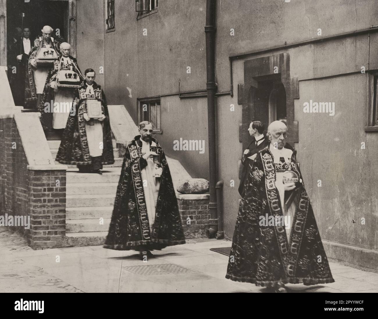 König George V. Krönung. Tragen der Krönungsregalia von der Jerusalem-Kammer zur Westminster-Abtei - das Foto zeigt eine Prozession von Männern, die aufwendige Gewänder tragen, die Jerusalum-Kammer verlassen und jeweils einen anderen Gegenstand für die Krönung des Königs tragen, 1911 Stockfoto