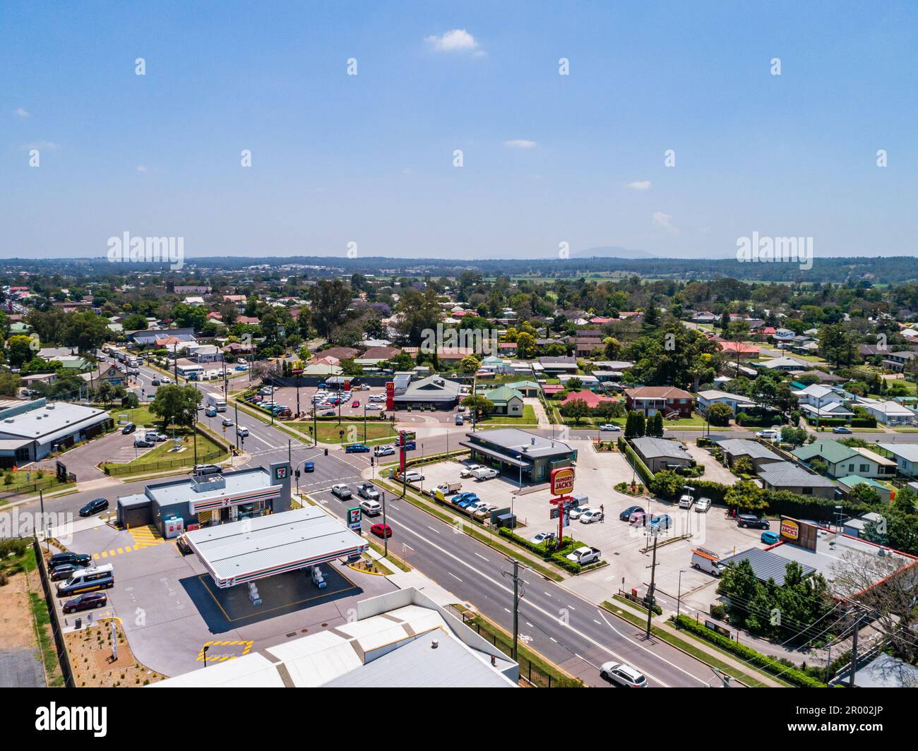 7Eleven Tankstelle und Fast-Food-Läden wie Hungry Jacks und Maccas mit Straße und Kreuzung mit Ampeln in Australian Town Stockfoto