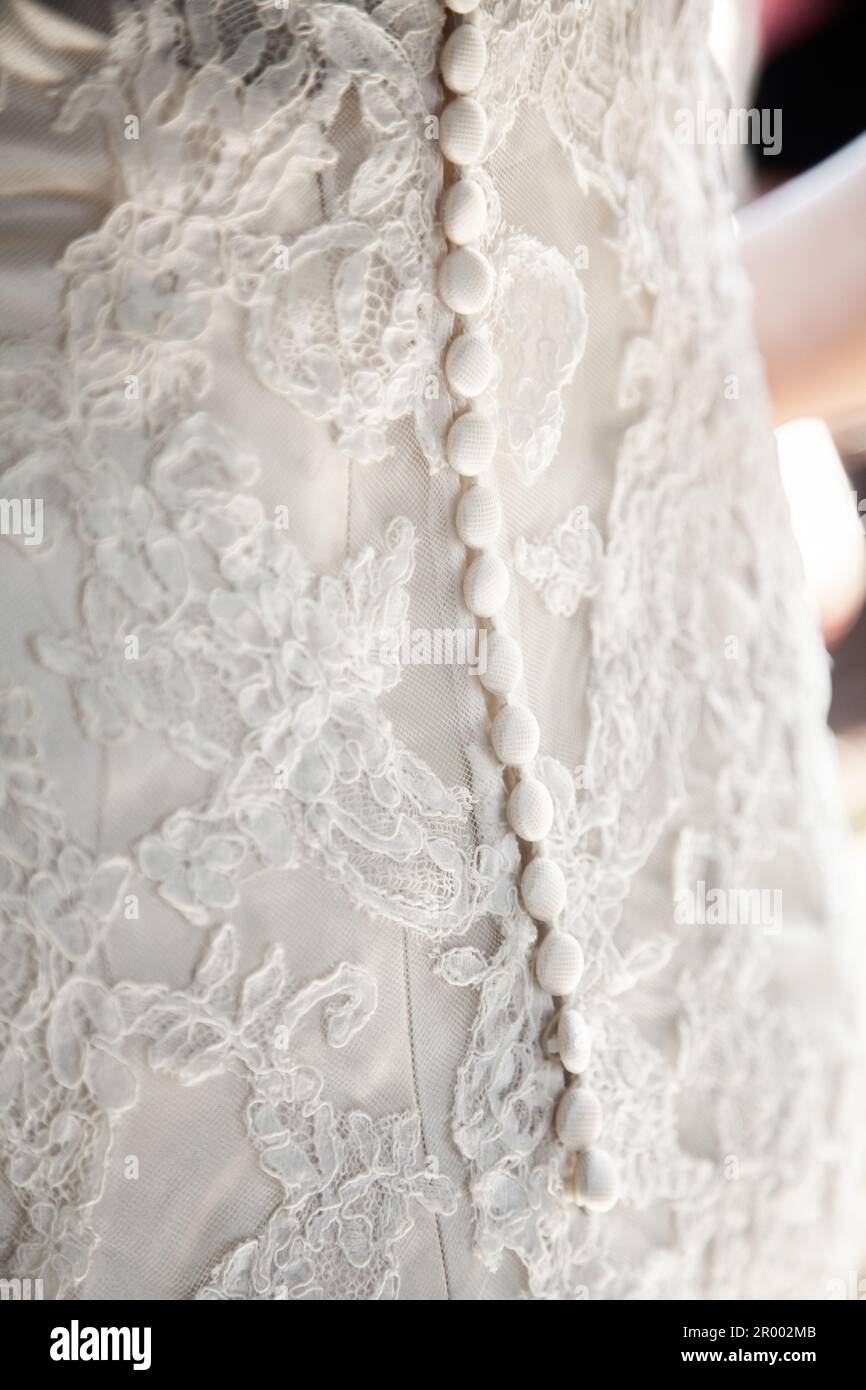Empfindliche Knöpfe und Spitzendetails auf der Rückseite eines Hochzeitskleids aus nächster Nähe Stockfoto