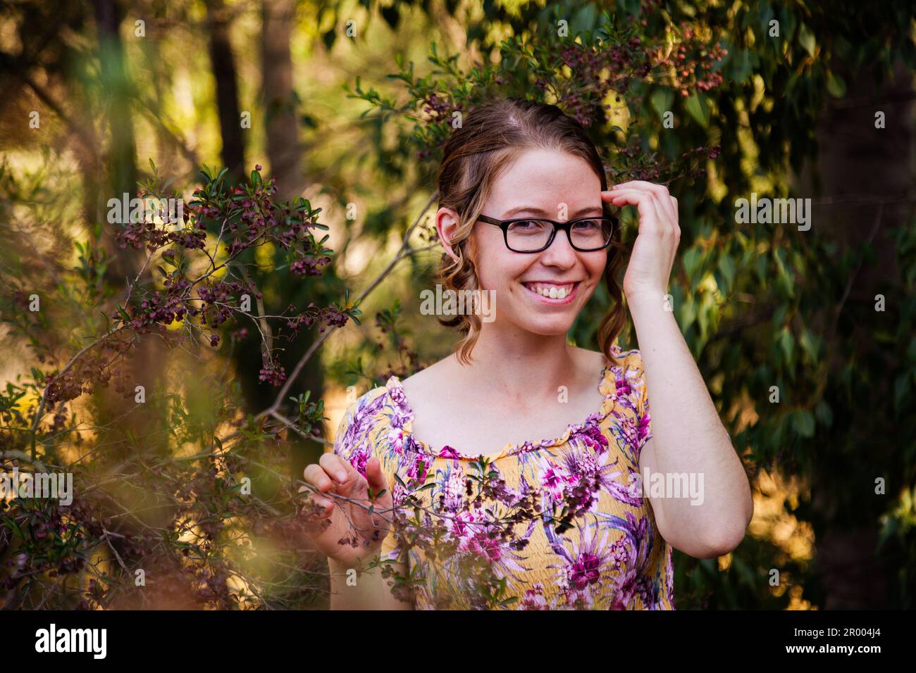 Ein Mädchen mit Brille im australischen Busch, das vor der Kamera lächelt Stockfoto