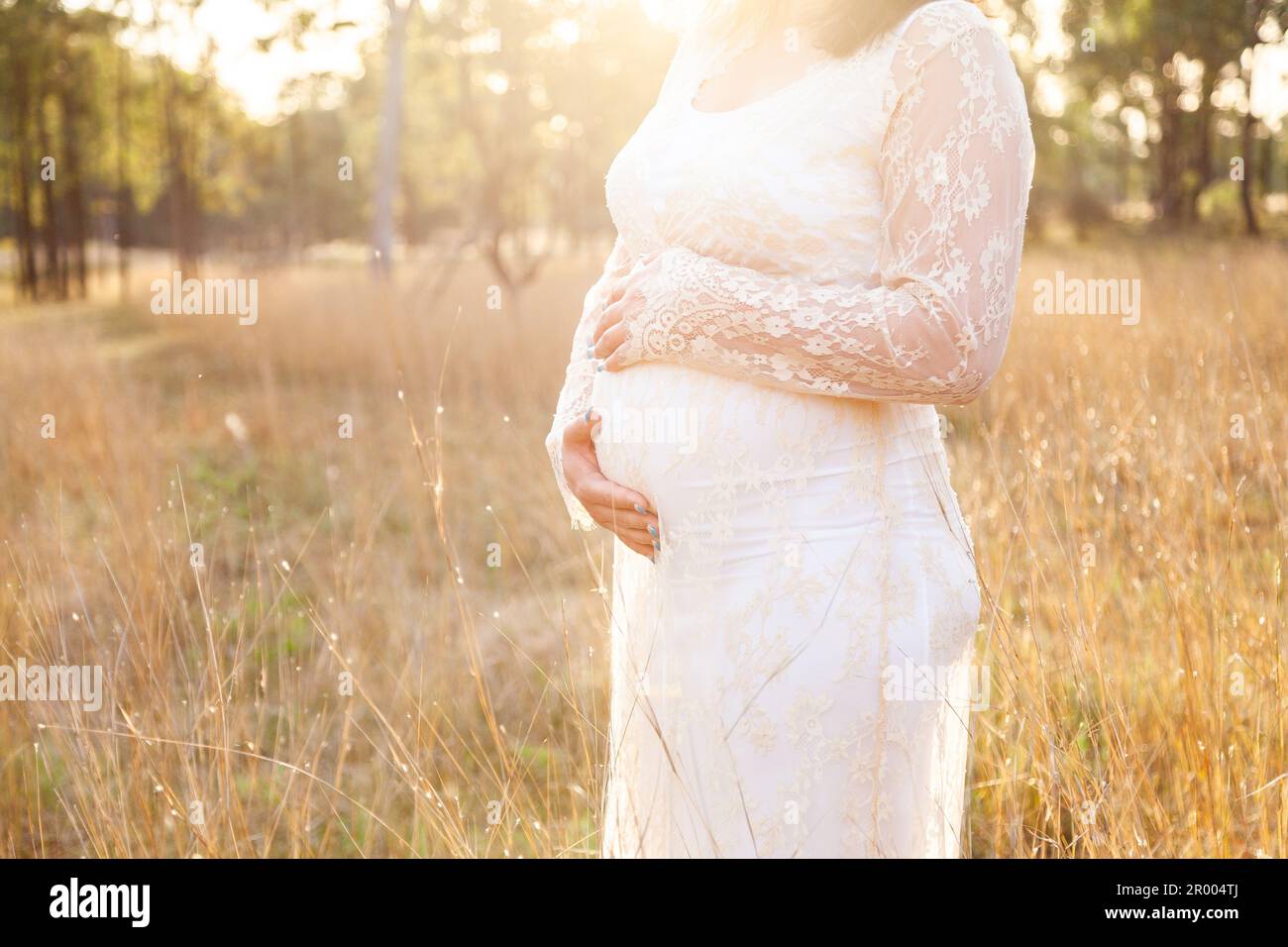 Schwangere Mutter mit Händen auf dem Bauch in australischer Koppel Stockfoto