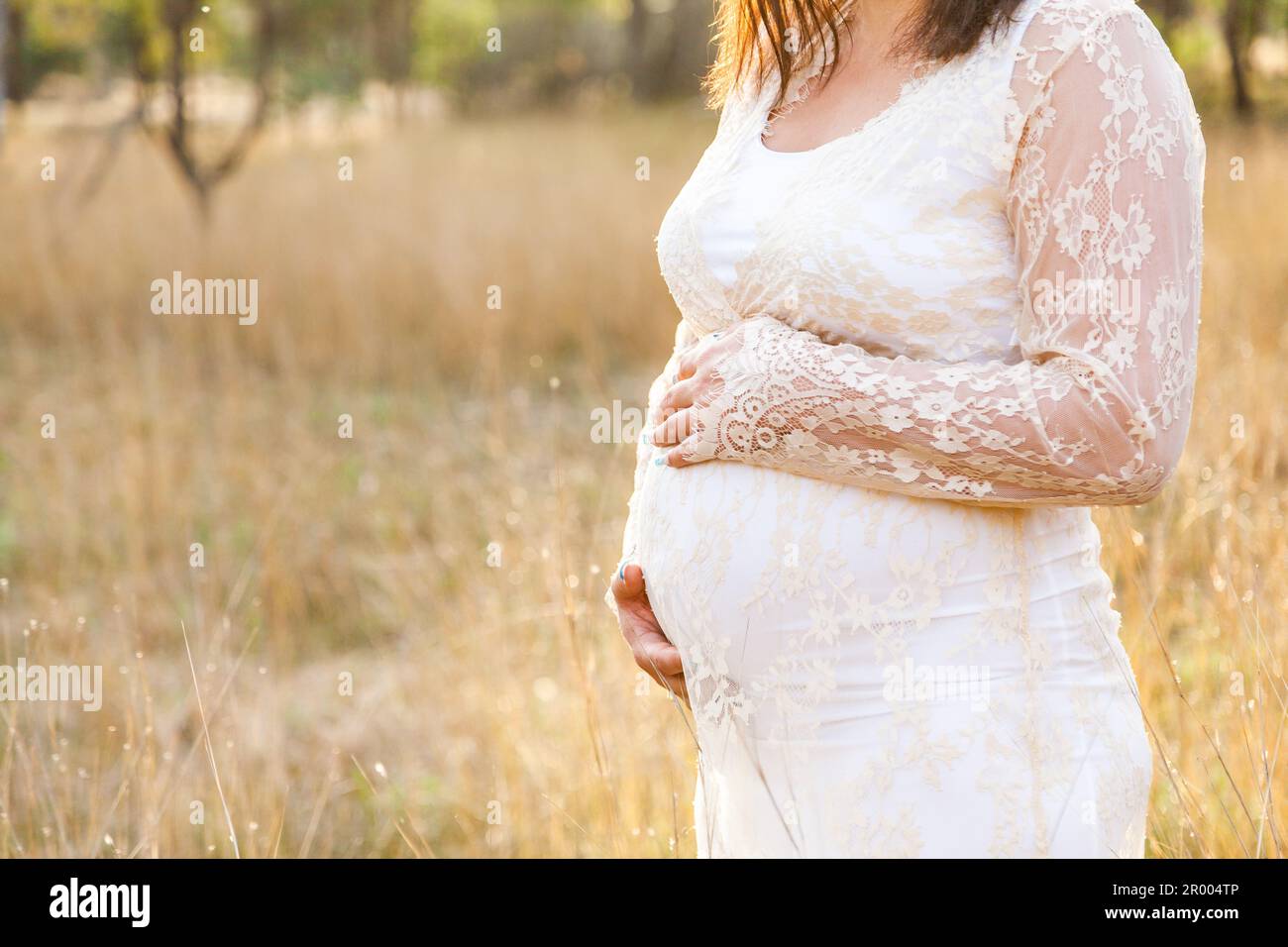 Schwangere Mutter mit Händen auf dem Bauch in australischer Koppel Stockfoto