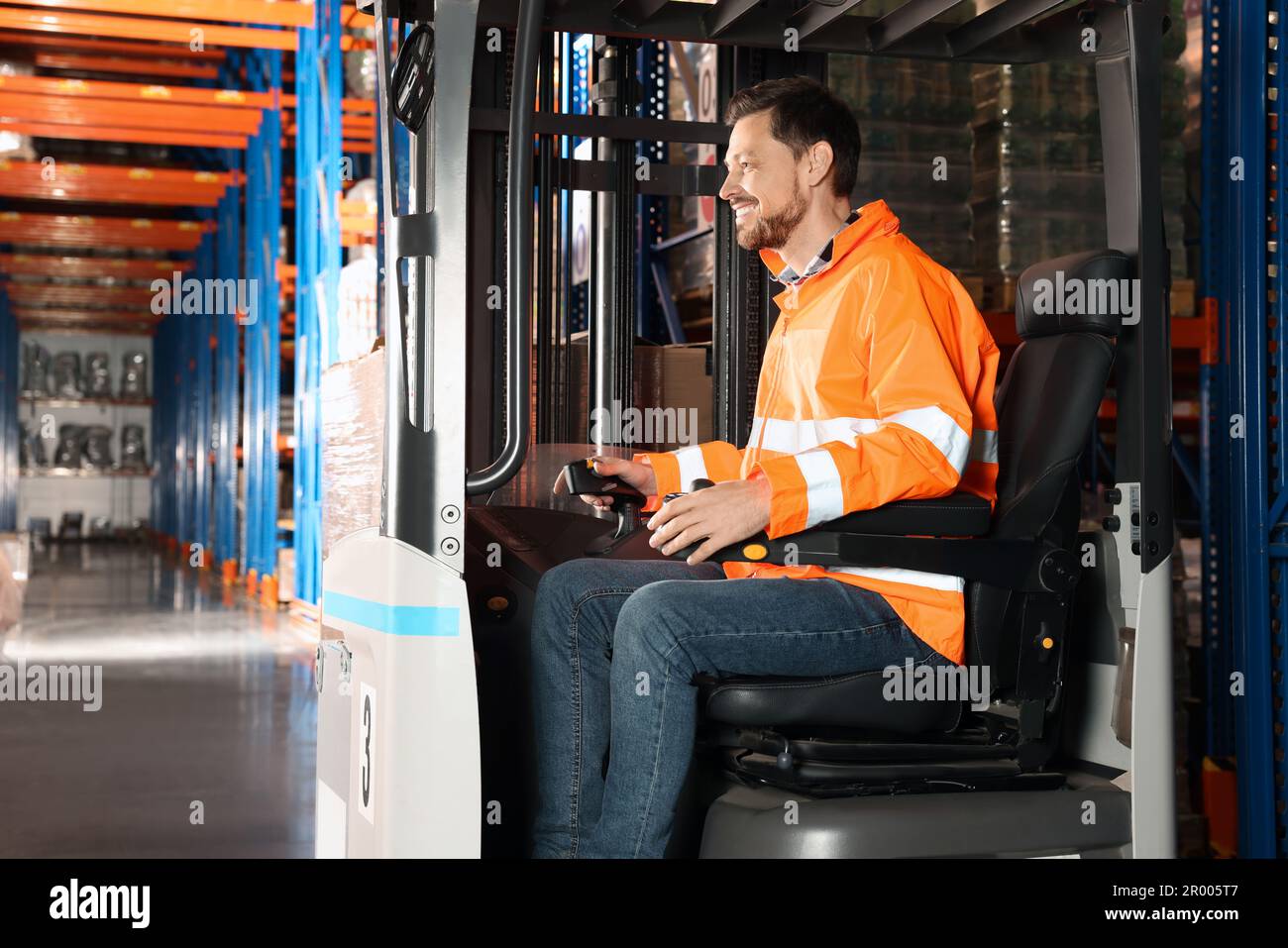 Glücklicher Arbeiter, der im Gabelstapler im Lager sitzt Stockfoto