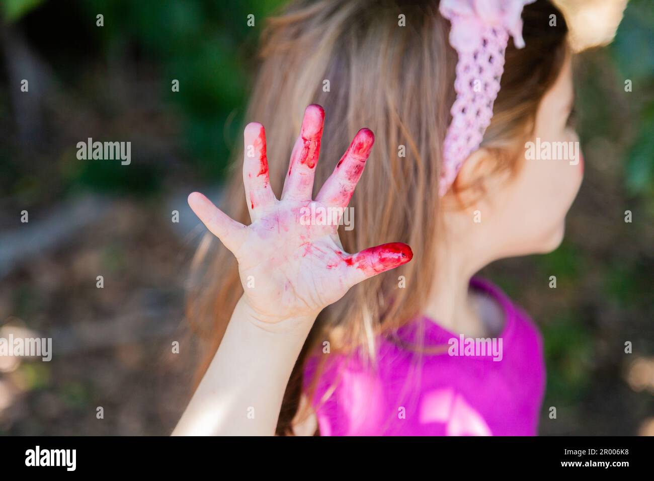 Die Hand eines kleinen Mädchens, das mit Fruchtsaftflecken bedeckt war, die von den Maulbeeren pflückten Stockfoto