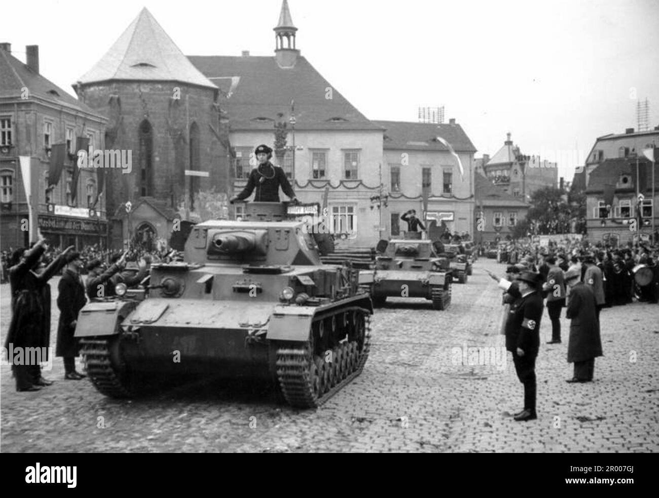 Schwere deutsche Panzer fahren am General Reinhardt am Adolf Hitler Platz vorbei, Komotau (heute Chomutow) in der Tschechoslowakei nach der Annexion des Sudetlands. Nach der Annexion Österreichs verlangte Hitler, dass er in die Region Sudeten der Tschechoslowakei aufgenommen wird. Auf der Münchner Konferenz im September 1938 stimmten die westlichen Mächte dem zu, und die nazis besetzten das Gebiet. Kurz nachdem Hitler sein Versprechen gebrochen hatte und in den Rest der Tschechoslowakei einmarschierte, widmete er sich Polen. Bundesarchiv, Bild 146-1970-050-41/CC-BY-SA 3,0 Stockfoto