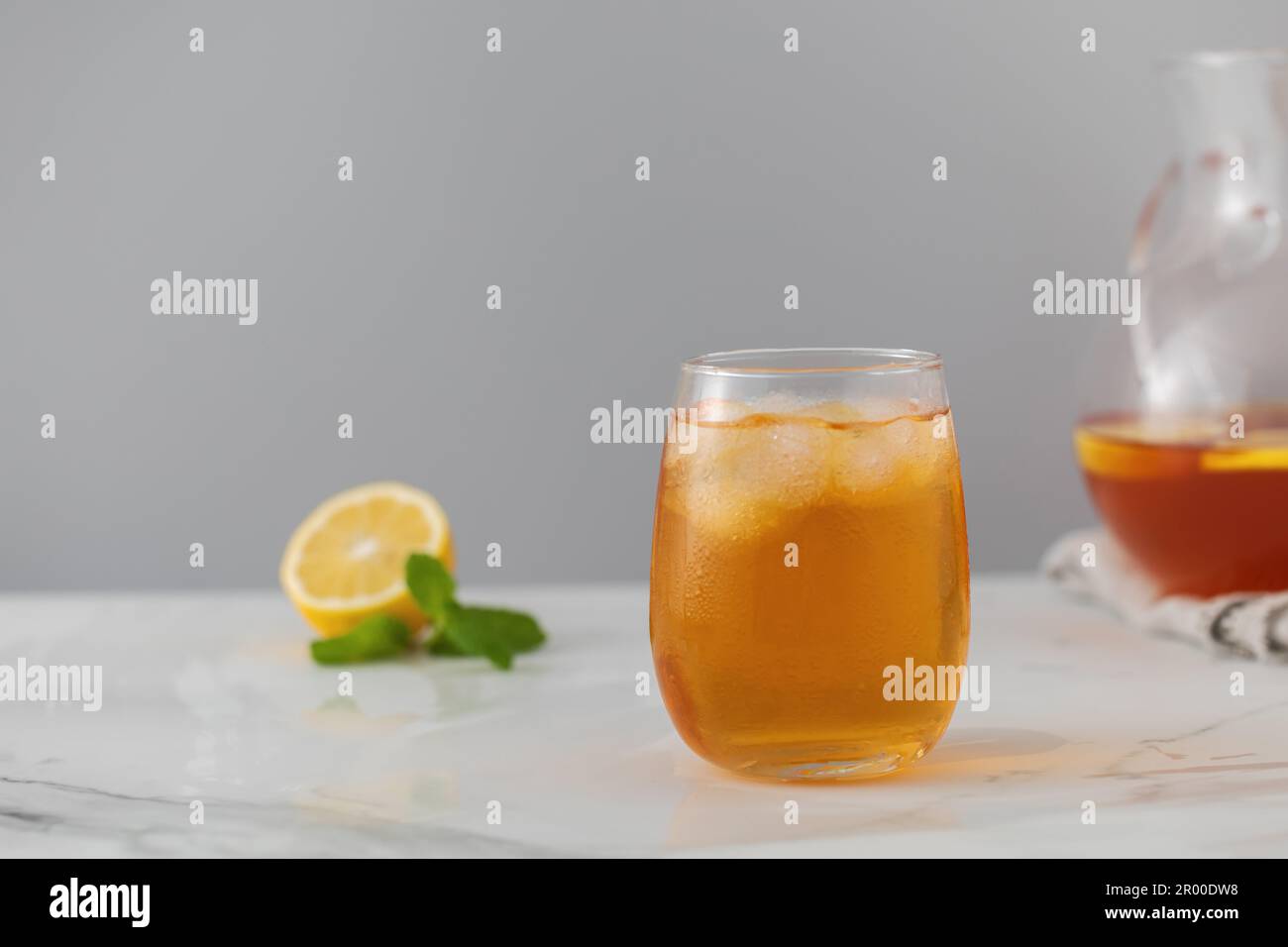 Ein Glas kalten Tee, Eiswürfel, Zitronenscheiben und einen Pfefferminzzweig. Kühle Sommergetränke. Stockfoto