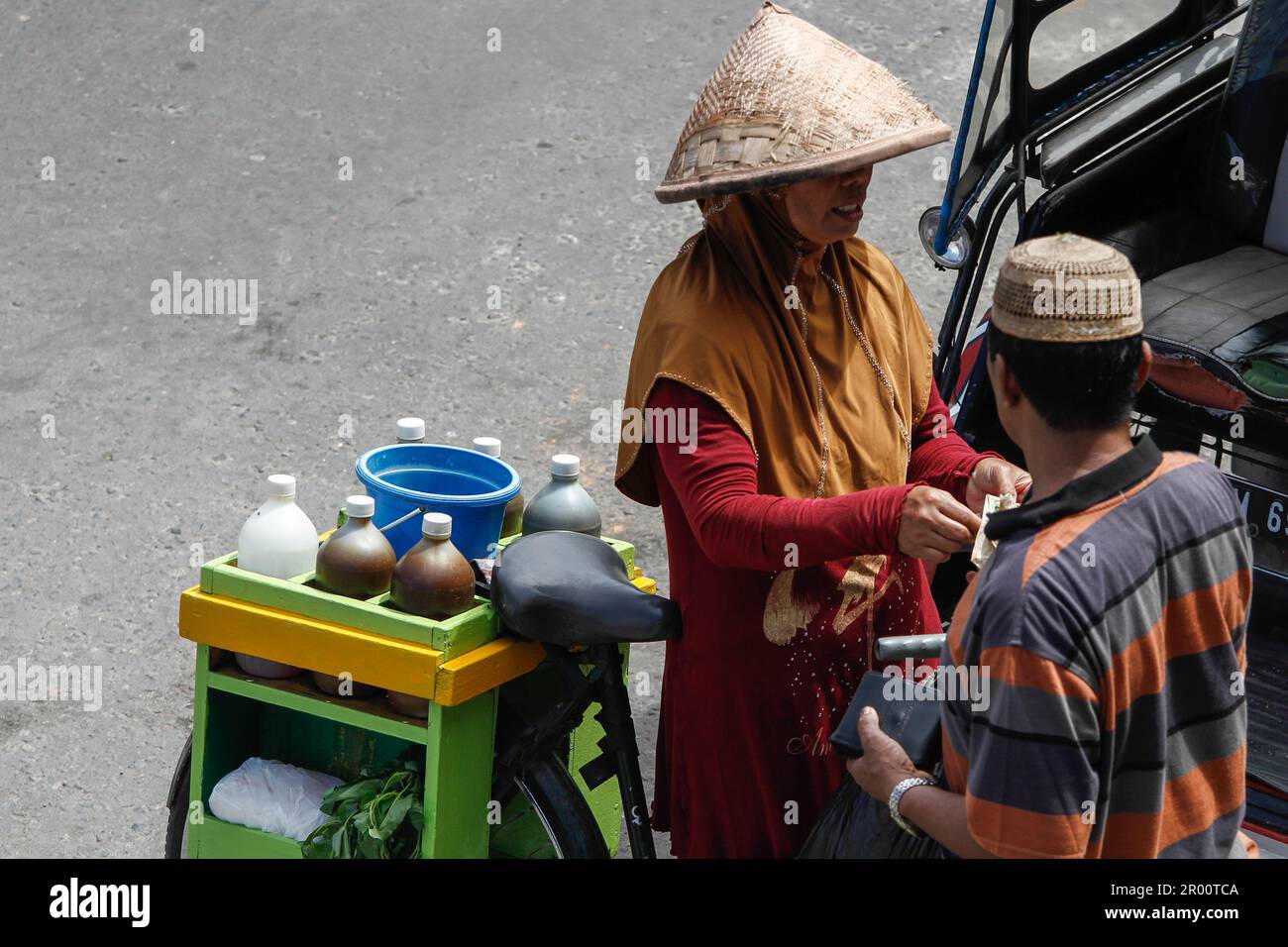 Kräutermedikamentenverkäufer und ihre Käufer. JAMU ist ein traditionelles Getränk in Indonesien, das aus verschiedenen Gewürzen und Pflanzen hergestellt wird. Stockfoto