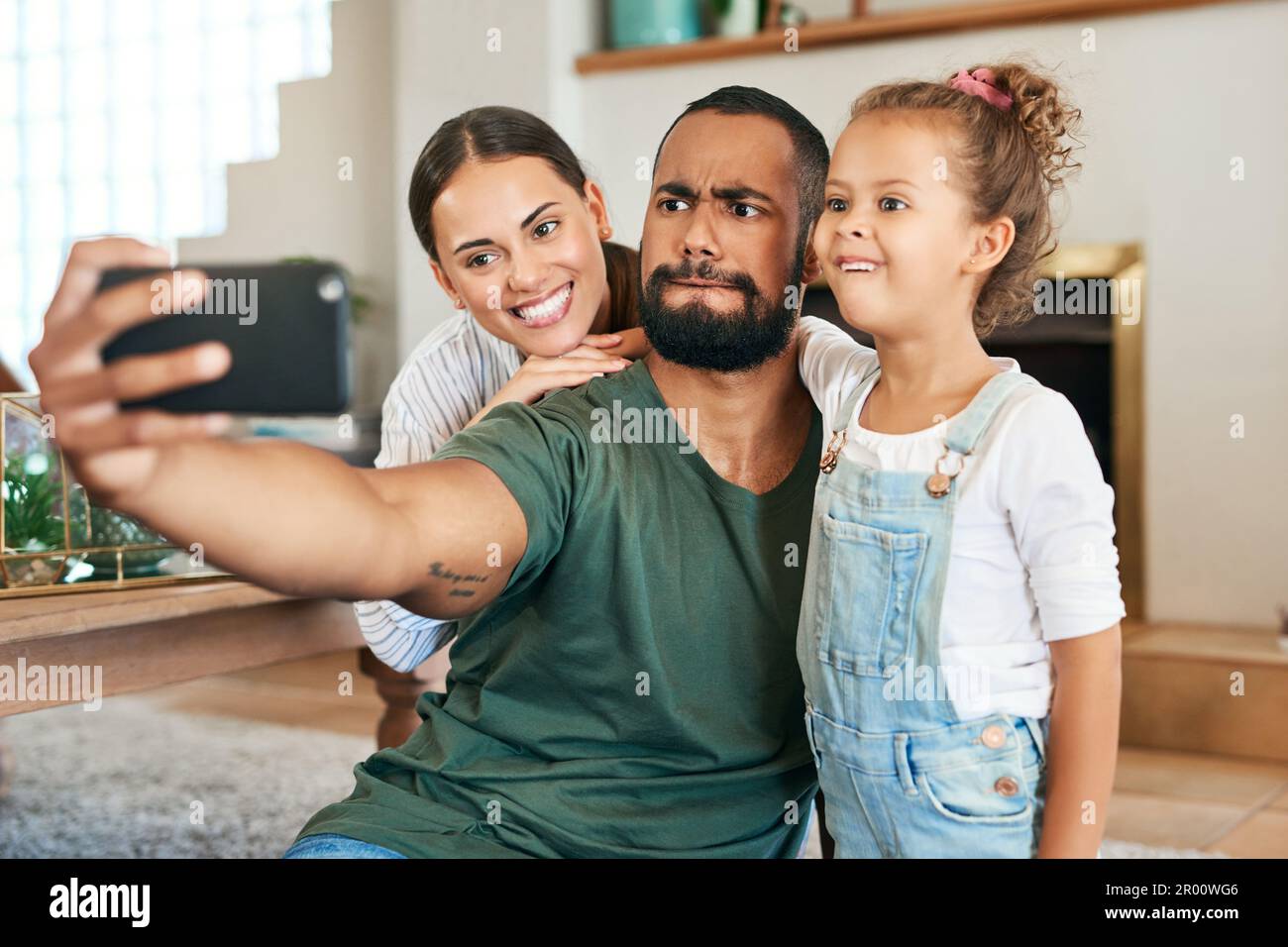 Glückliche, lustige Erinnerungen sind am besten zu schätzen. Eine glückliche Familie, die lustige Gesichter macht, während sie zu Hause Selfies macht. Stockfoto