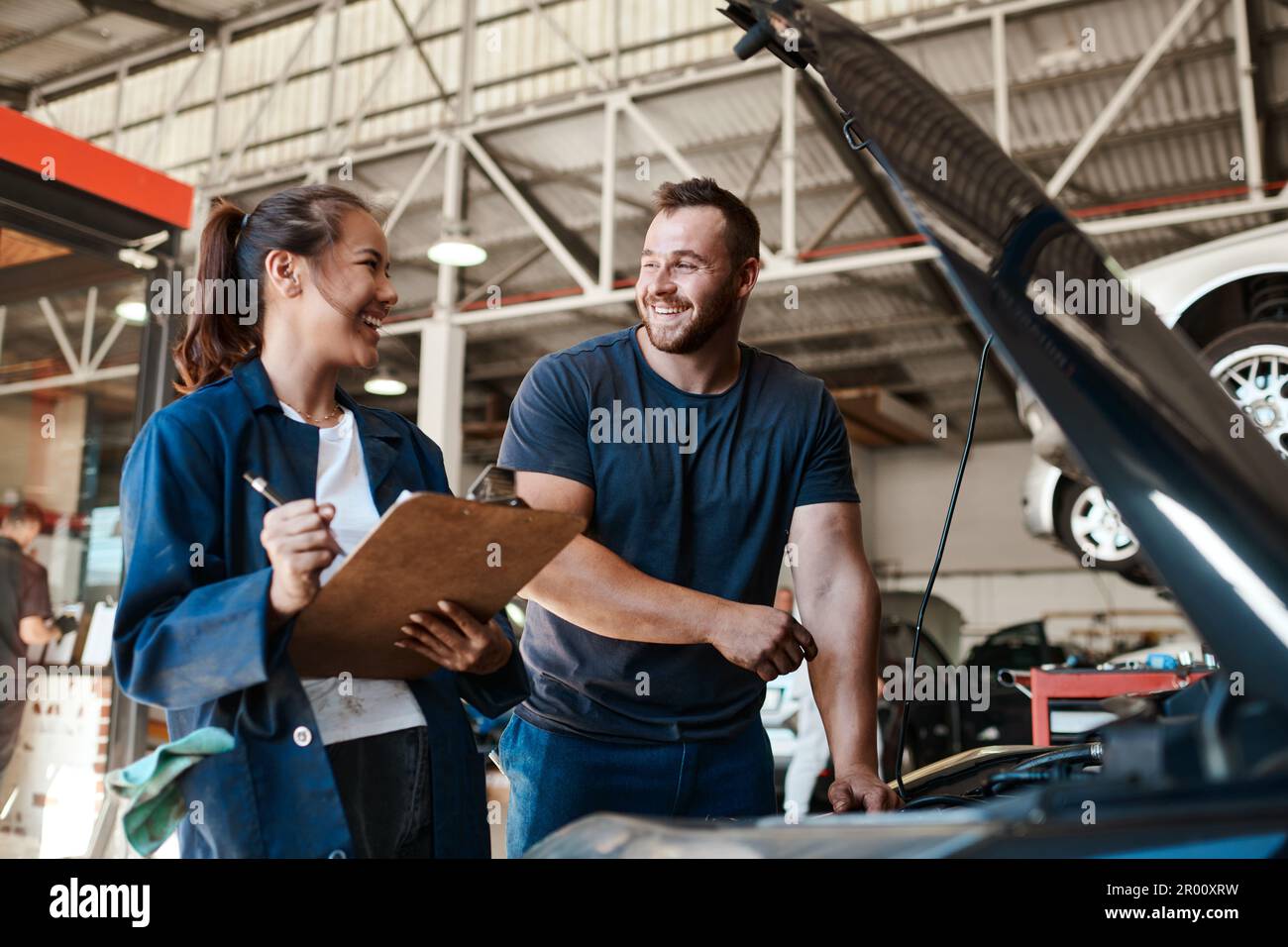 Wir warten alle Marken und Modelle. Zwei Mechaniker arbeiten zusammen an einem Auto in einer Autowerkstatt. Stockfoto